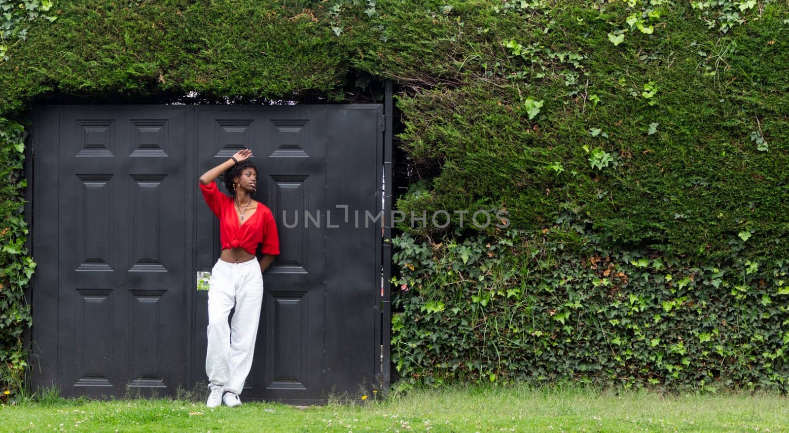 black girl in white and red clothes leaning against a black door. High quality photo