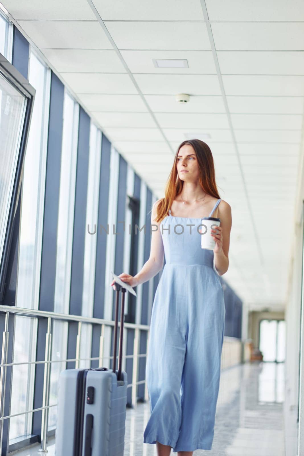 Woman holding coffee. Young traveler is on the entrance hall in the airport.