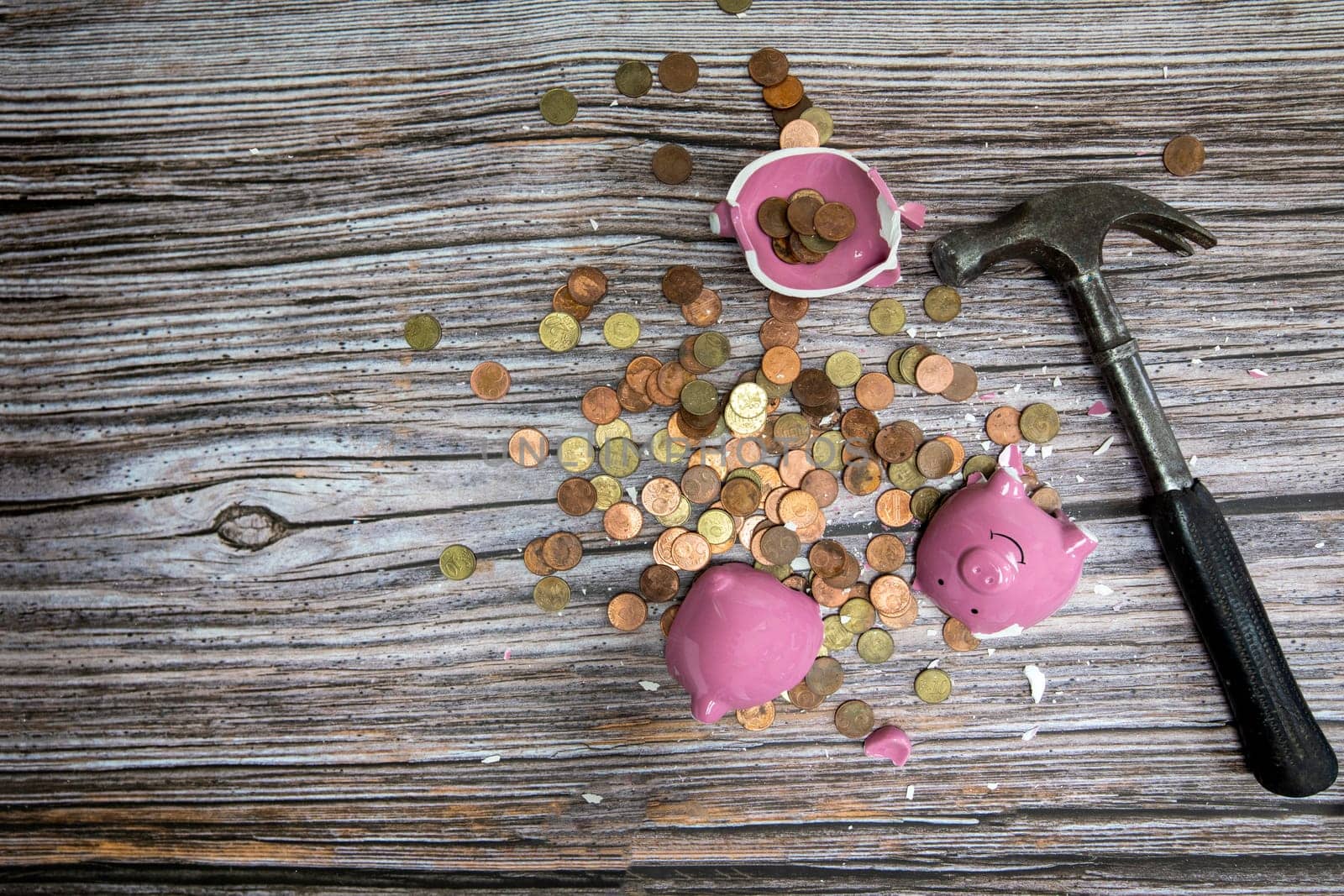 Broken piggy bank smashed into pieces with hammer, with cash and coins on wooden background top view with copy space, money savings concept by Annebel146