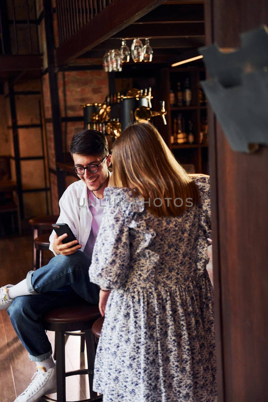Cheerful young people in casual clothes sitting in the pub.