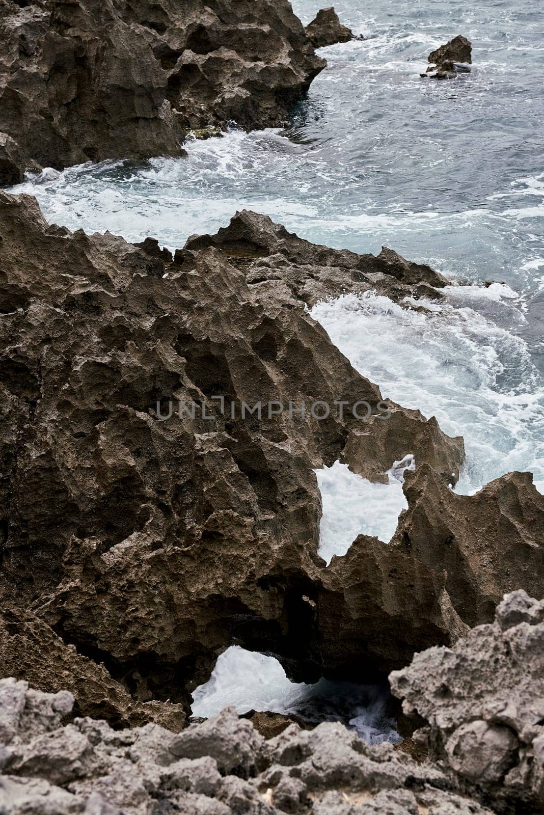 Waves breaking on the shore on a pebble road. water foam, wild waters, texture, ocean, sea, rocks,danger