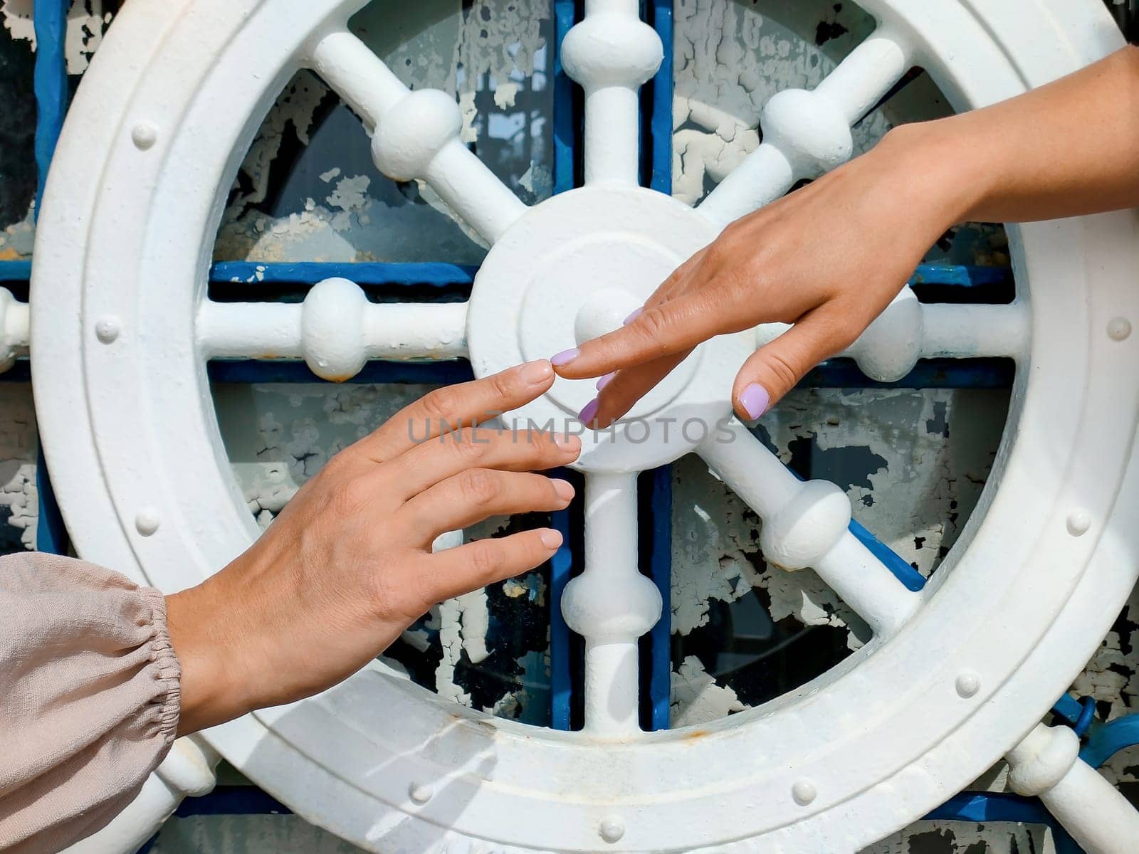 Concept of human relationships, partnership and unity, two female hands stretch each other their index fingers against background of a symbolic steering wheel, close-up