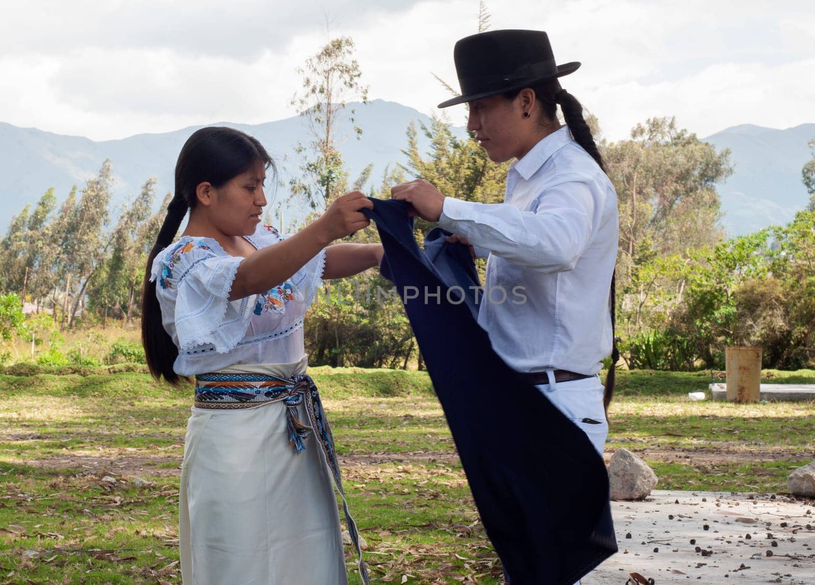 Indigenous man lovingly helps his wife get ready in her traditional dress for a cultural celebration by Raulmartin