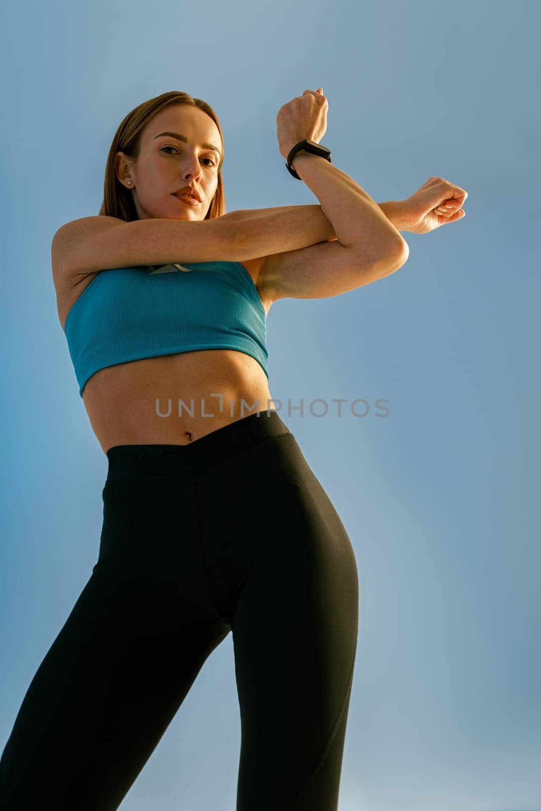 Attractive woman doing warm up hands exercises and stretching her body preparing to gym in studio by Yaroslav_astakhov