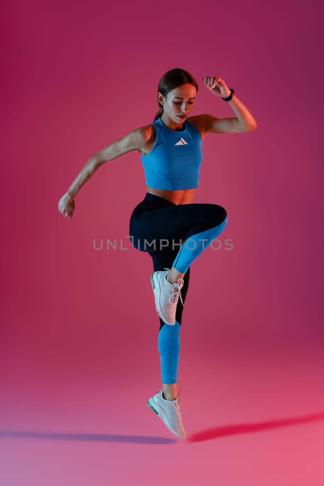 Athletic active fitness woman jumping on studio background . Dynamic movement. High quality photo
