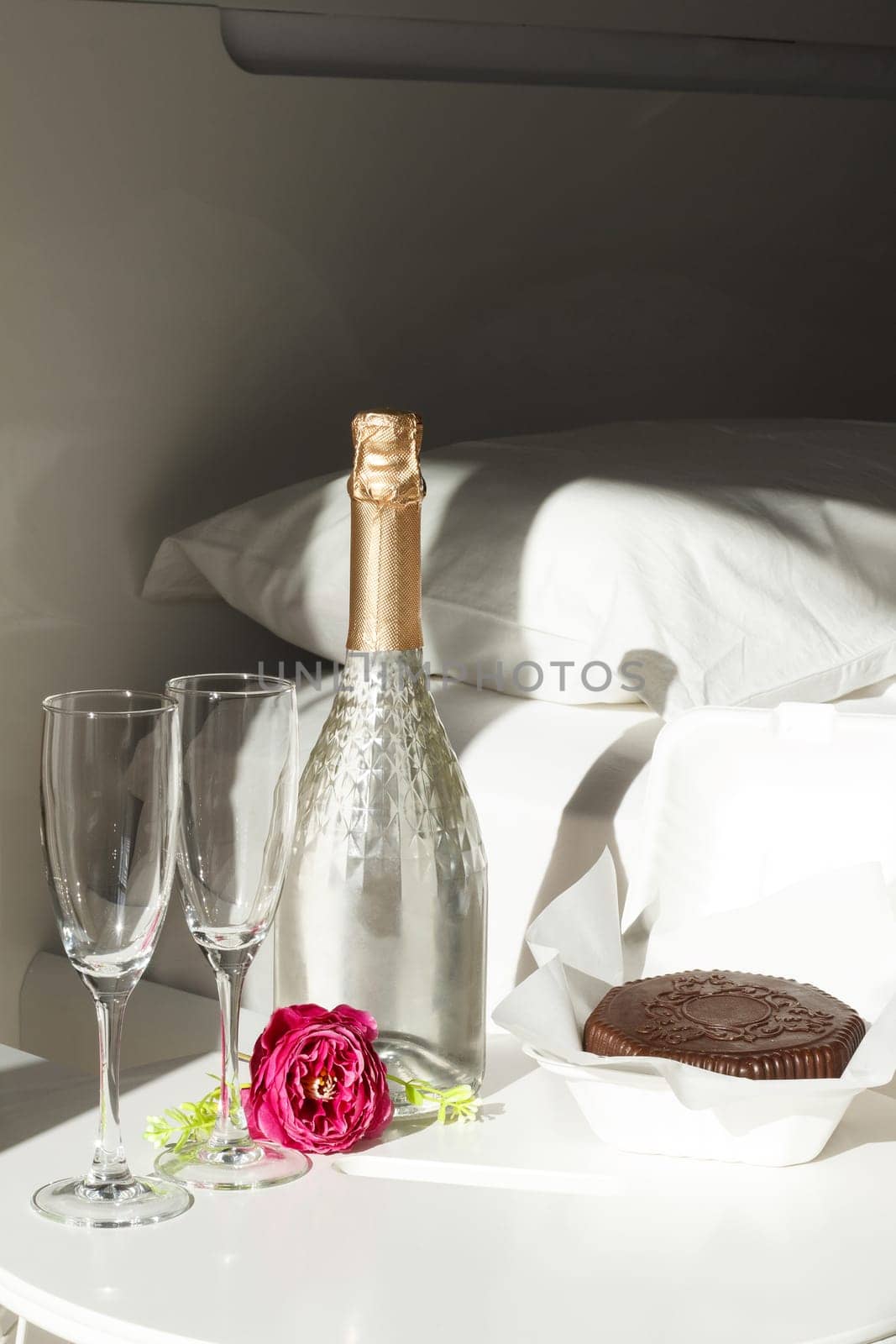 Two glasses with a bottle of champagne and a chocolate dessert in a luxury hotel room. Dating, romance, honeymoon, Valentine's day.