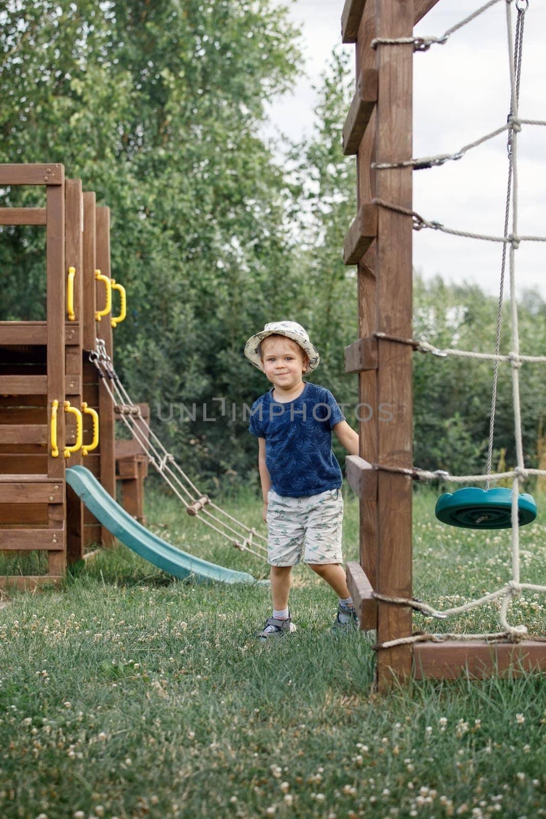 A happy child is running around on his playground on a sunny summer day. Nice day, green nature garden, boy playing happily.