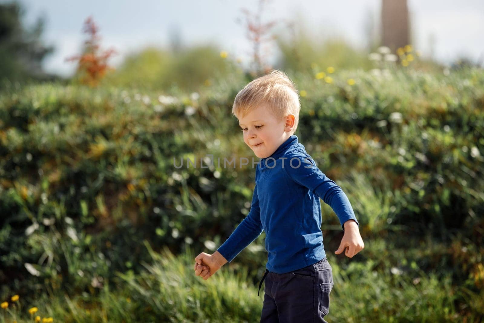 Cute boy running across grass und smiling.