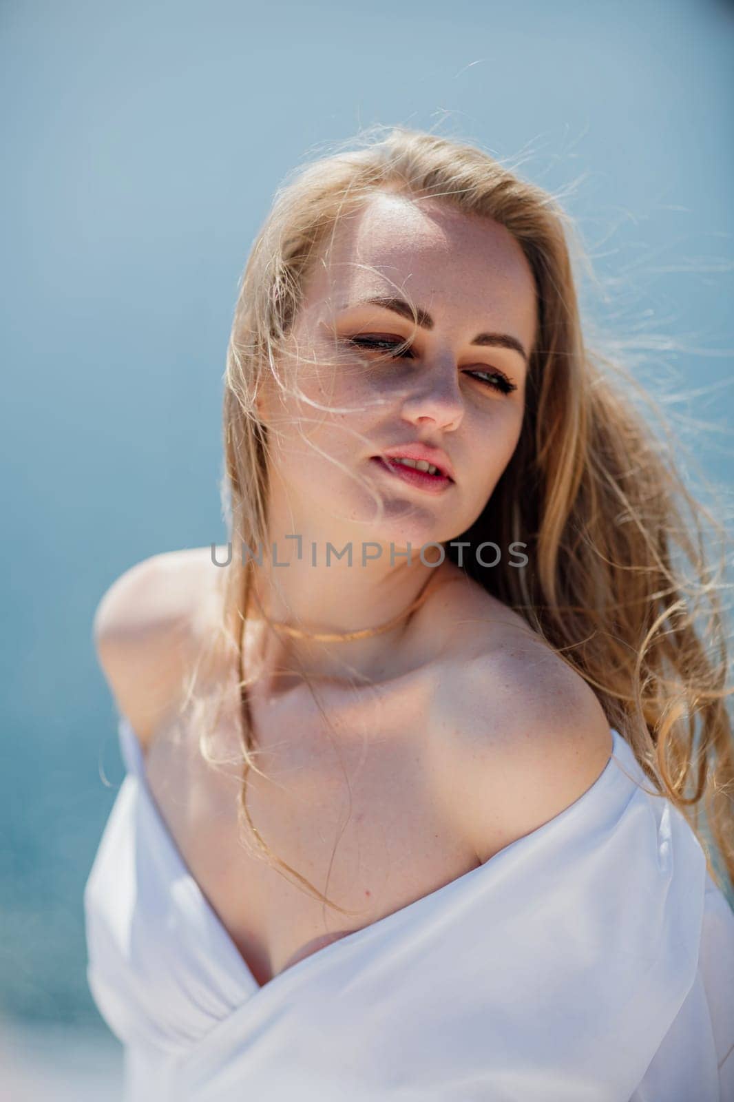 Portrait of a blond woman at the sea, a woman makes photos for memory from a trip to the sea to show to friends
