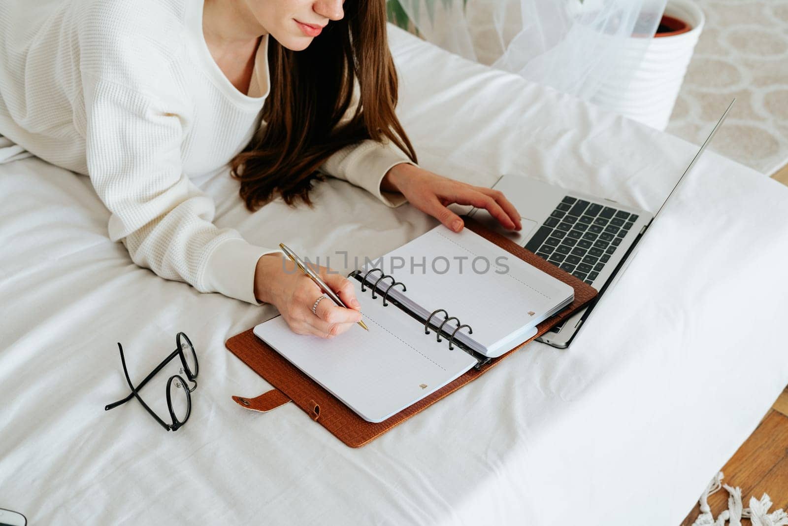 Distance learning online education and work. Business woman writes to do list in notebook. Cropped freelance girl with laptop at home office. Using computer and online shops. Copy space blank mockup.