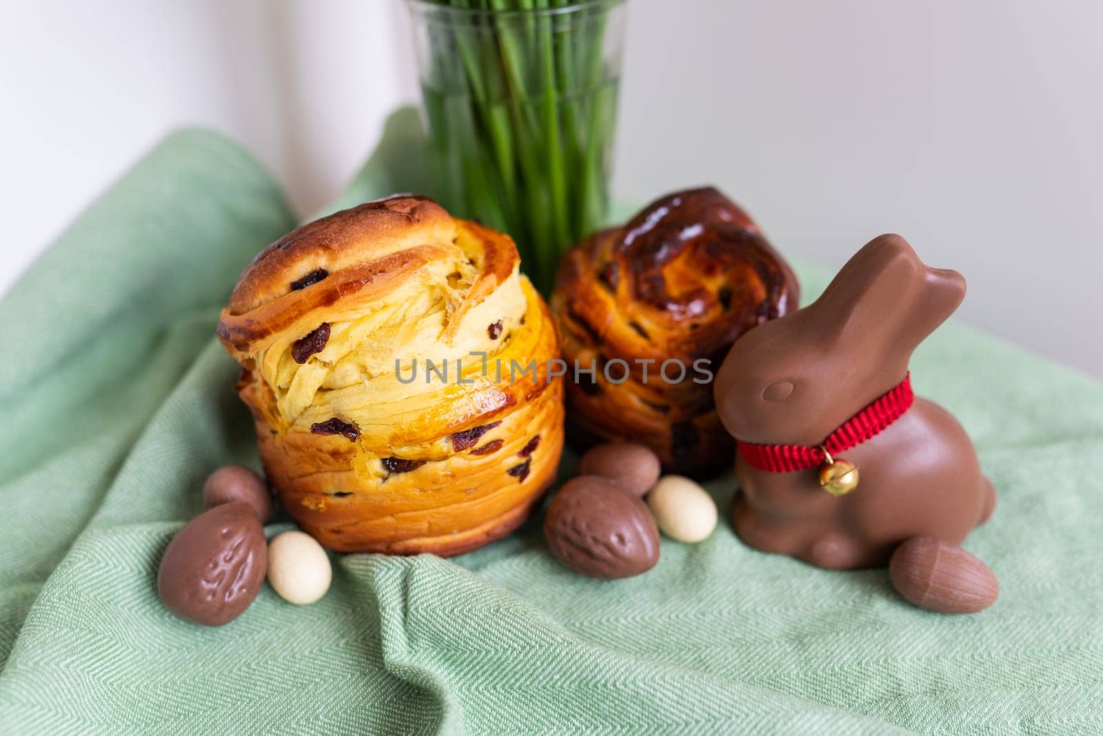 Homemade Easter traditional pastries lie on a green napkin with a bouquet of flowers, a rabbit, chocolate eggs. Easter baking and decoration. by sfinks