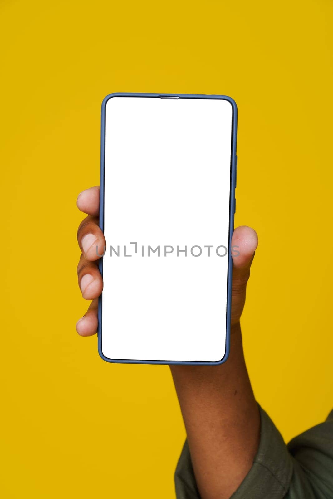 African man's hand holding phone with white blank screen on yellow background. Close up. Advertising concept. High quality photo