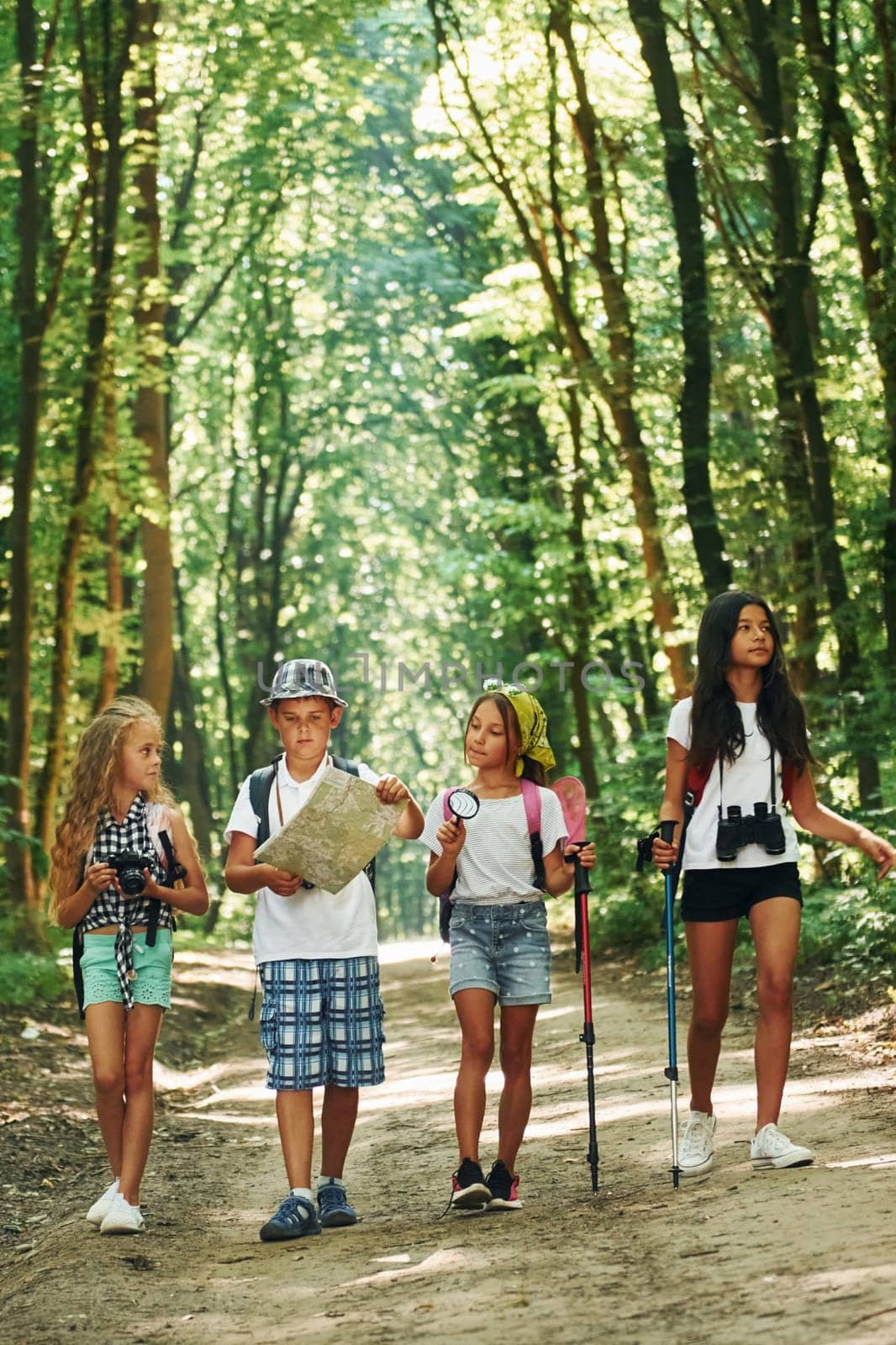 With map. Kids strolling in the forest with travel equipment.