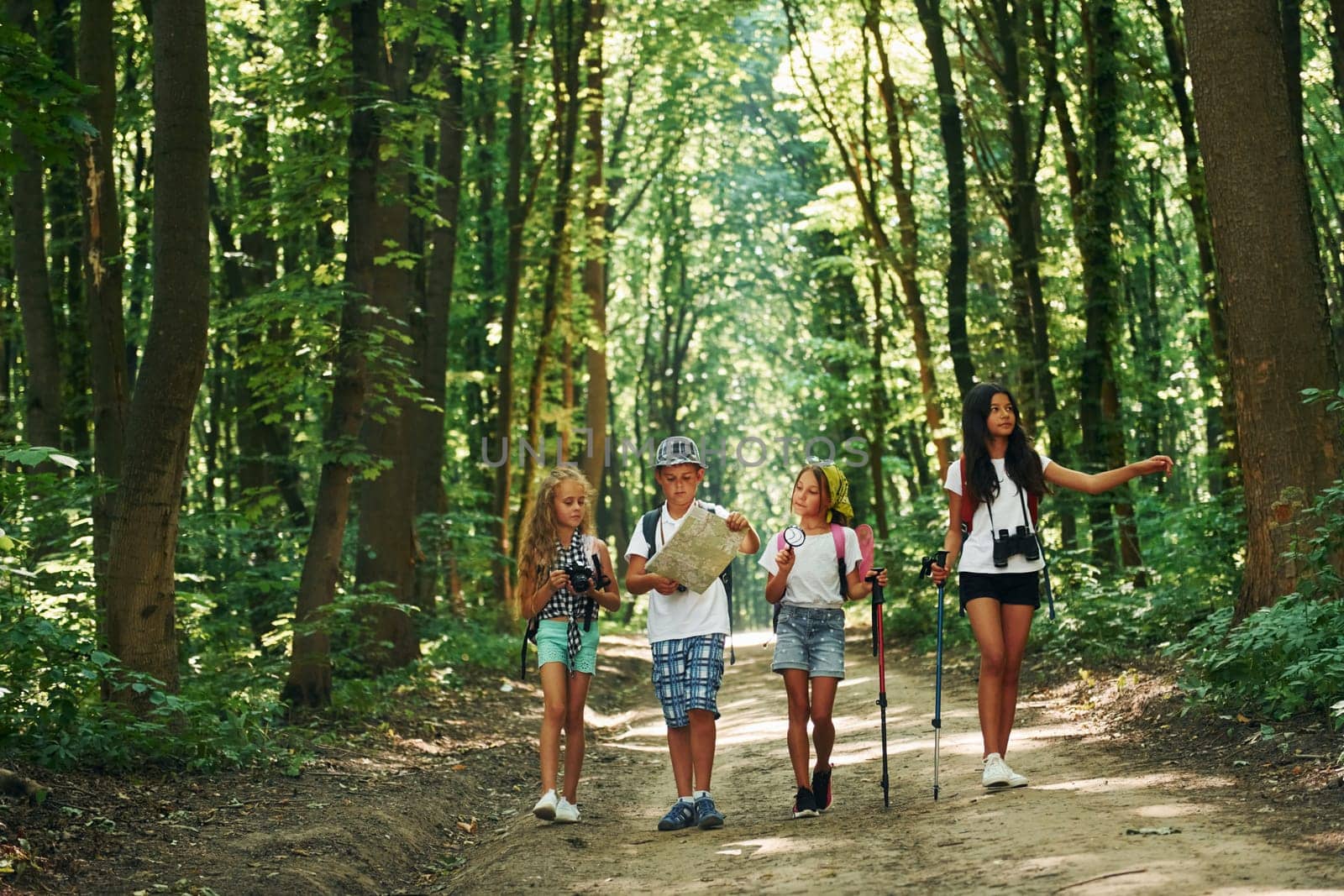 With map. Kids strolling in the forest with travel equipment.