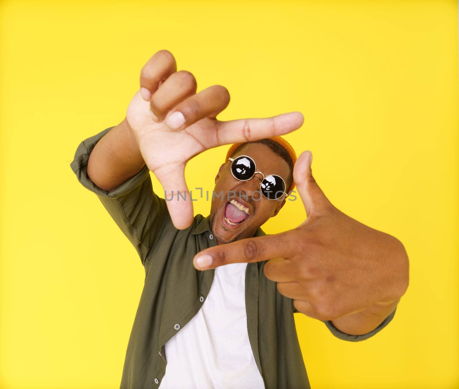 Creative young man on yellow background is seen making composition frame from his fingers, showcasing his artistic and imaginative abilities. Concept of innovation and inspiration, using hand gestures as non-verbal communication tool. High quality photo