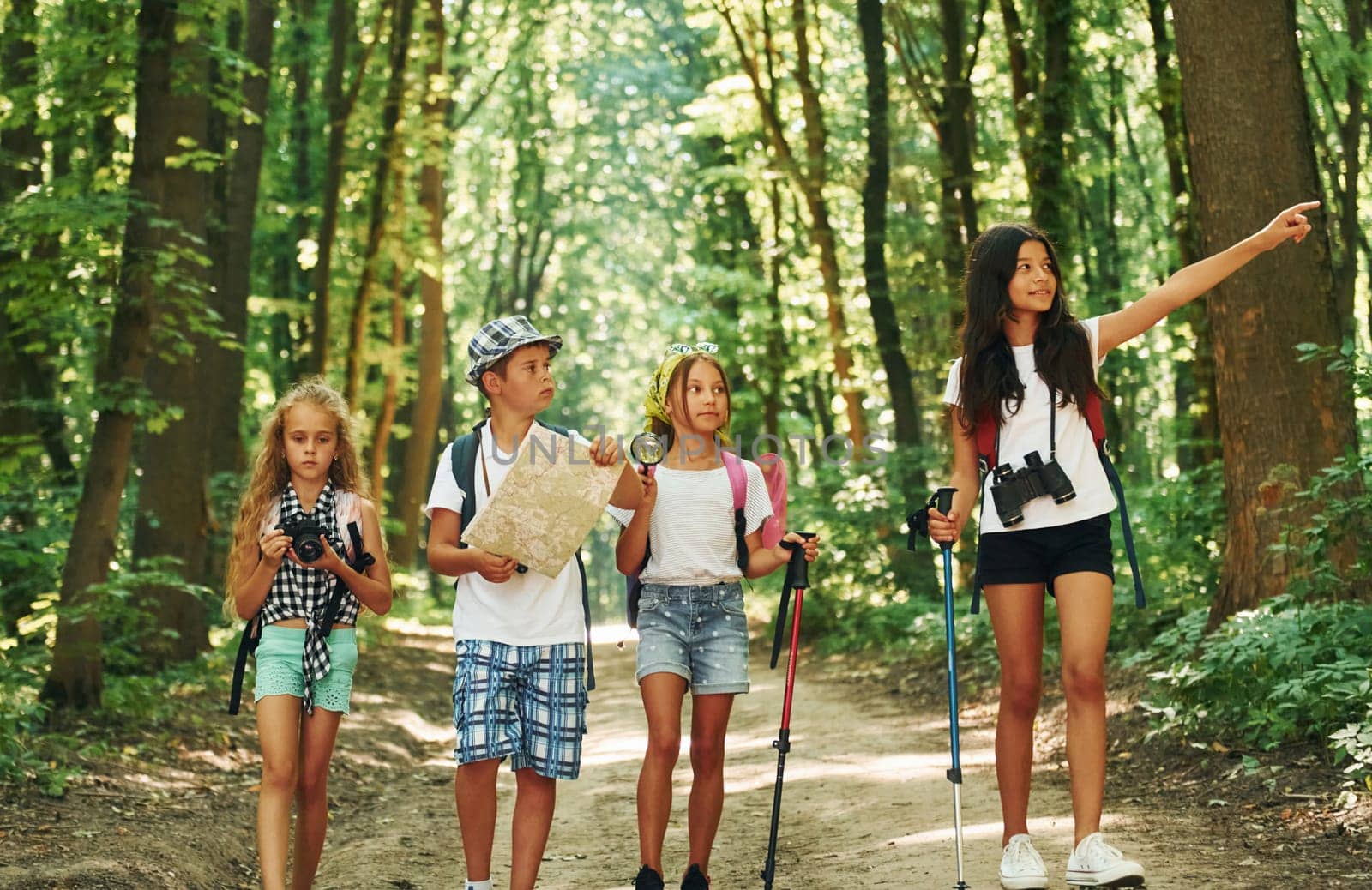 With map. Kids strolling in the forest with travel equipment.