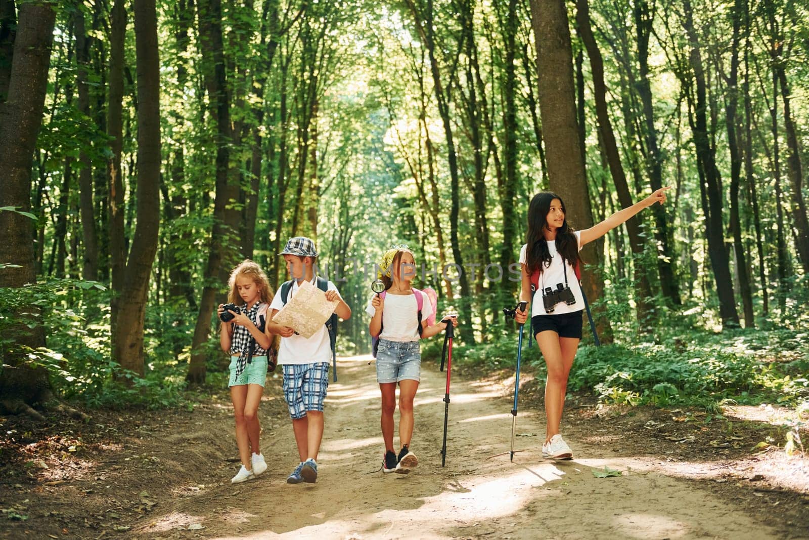With map. Kids strolling in the forest with travel equipment.