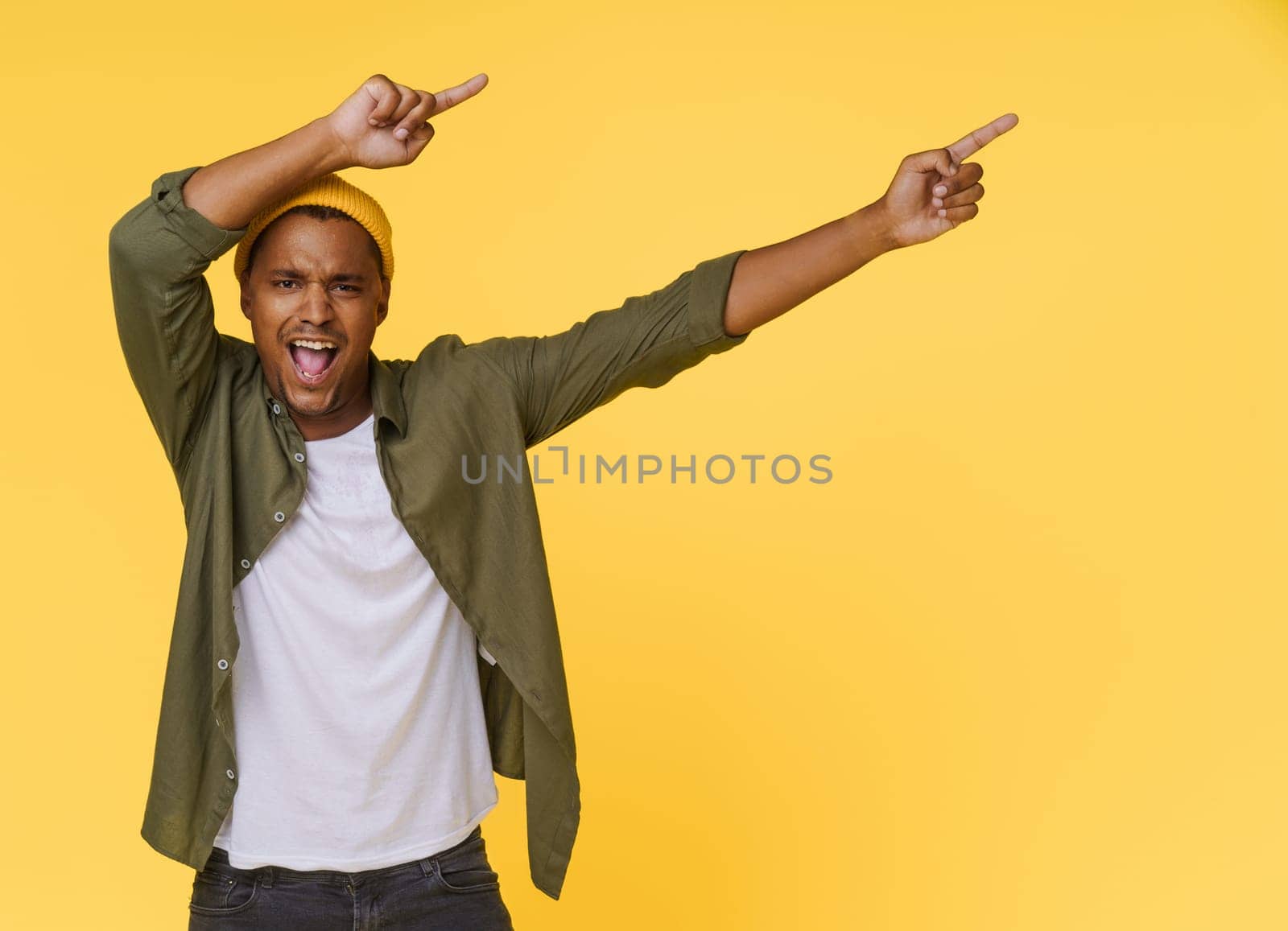 Excited African man points two hands to the side to copy space on yellow background. Product placing, advertising concept. High quality photo