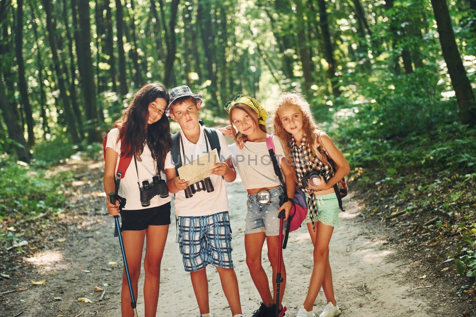 Front view. Kids strolling in the forest with travel equipment.