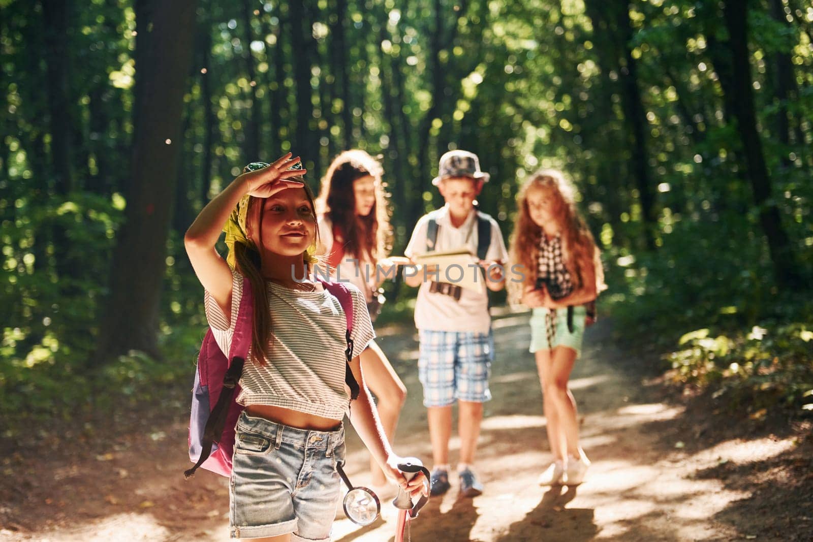 Girl looking far away. Kids strolling in the forest with travel equipment by Standret