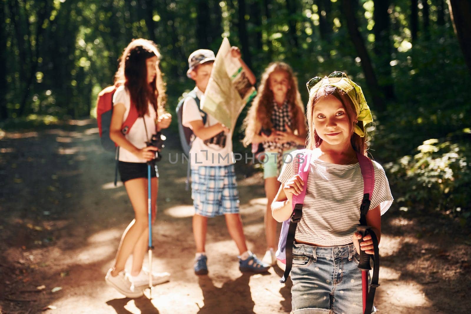 Posing for the camera. Kids strolling in the forest with travel equipment by Standret