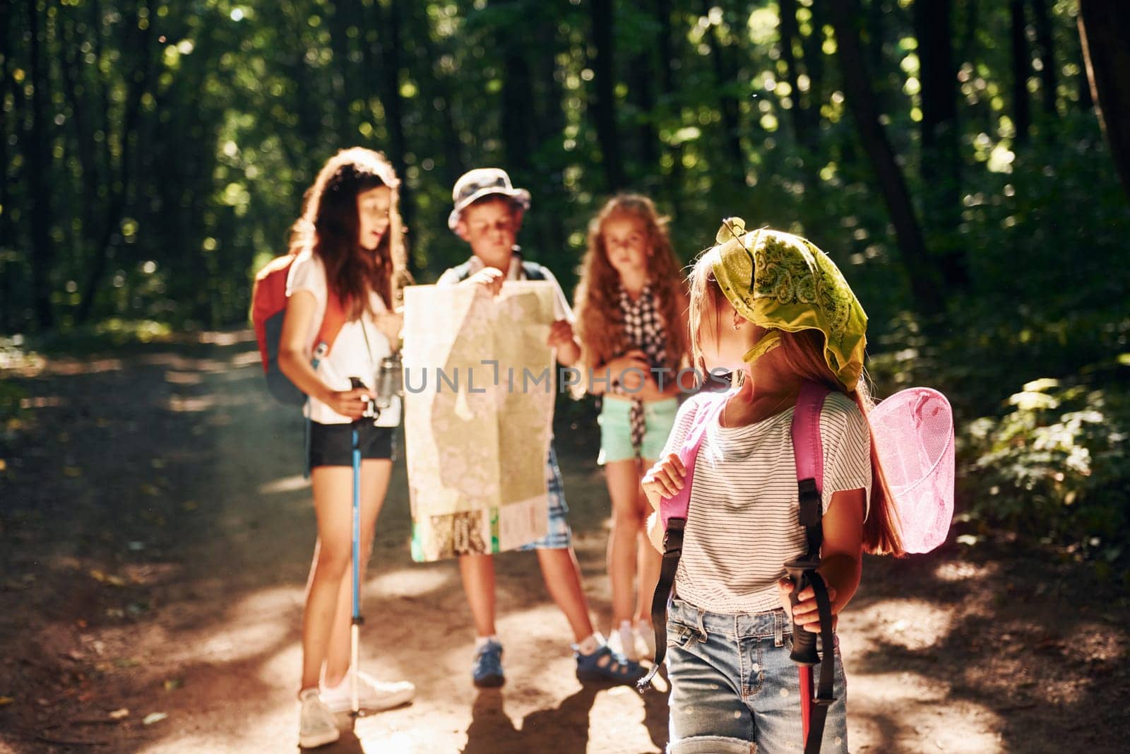 Posing for the camera. Kids strolling in the forest with travel equipment.