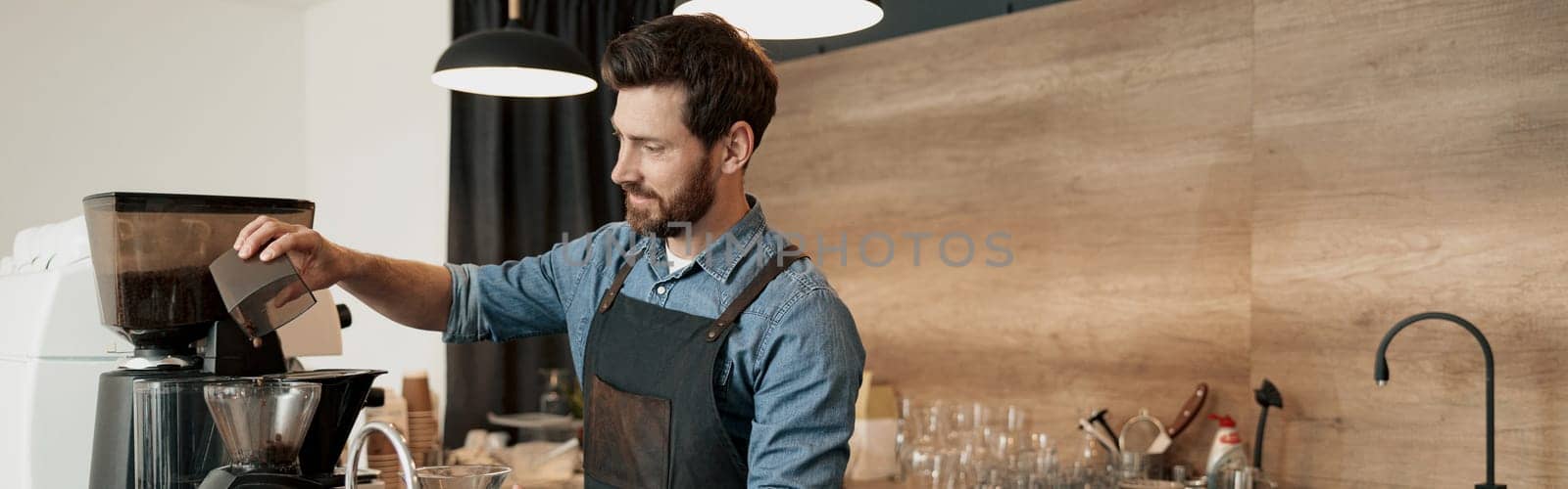 Barista grinds coffee beans before making coffee at coffeehouse