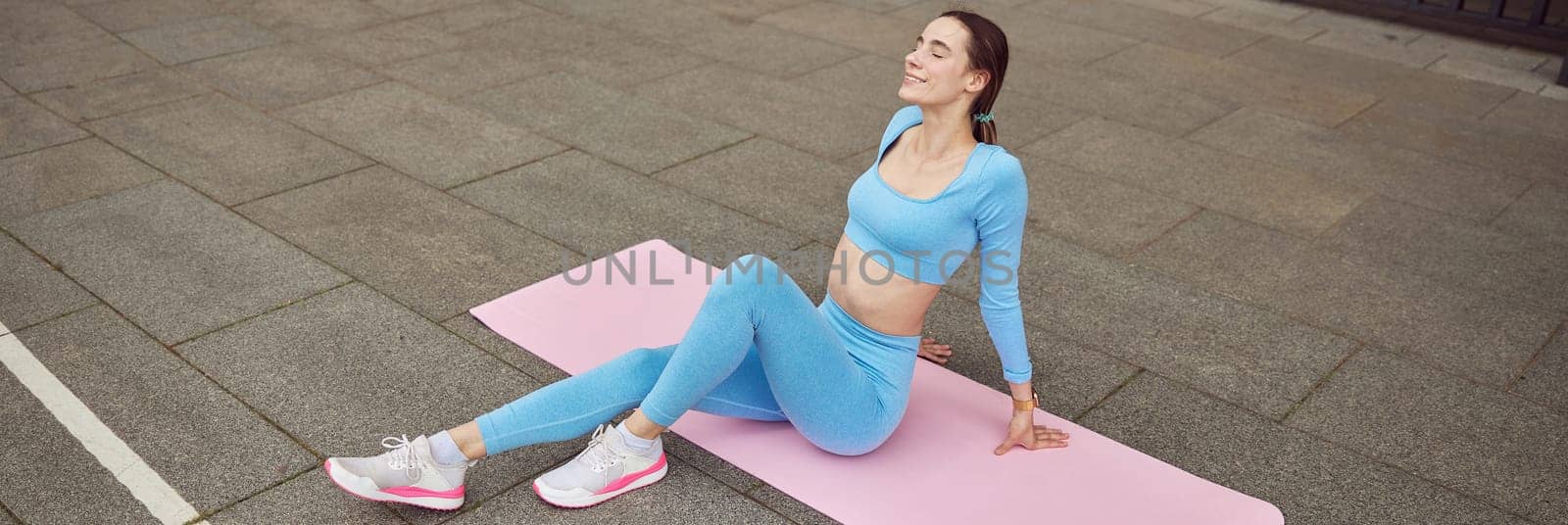 Beautiful fit caucasian woman is doing exercises outdoors at the city