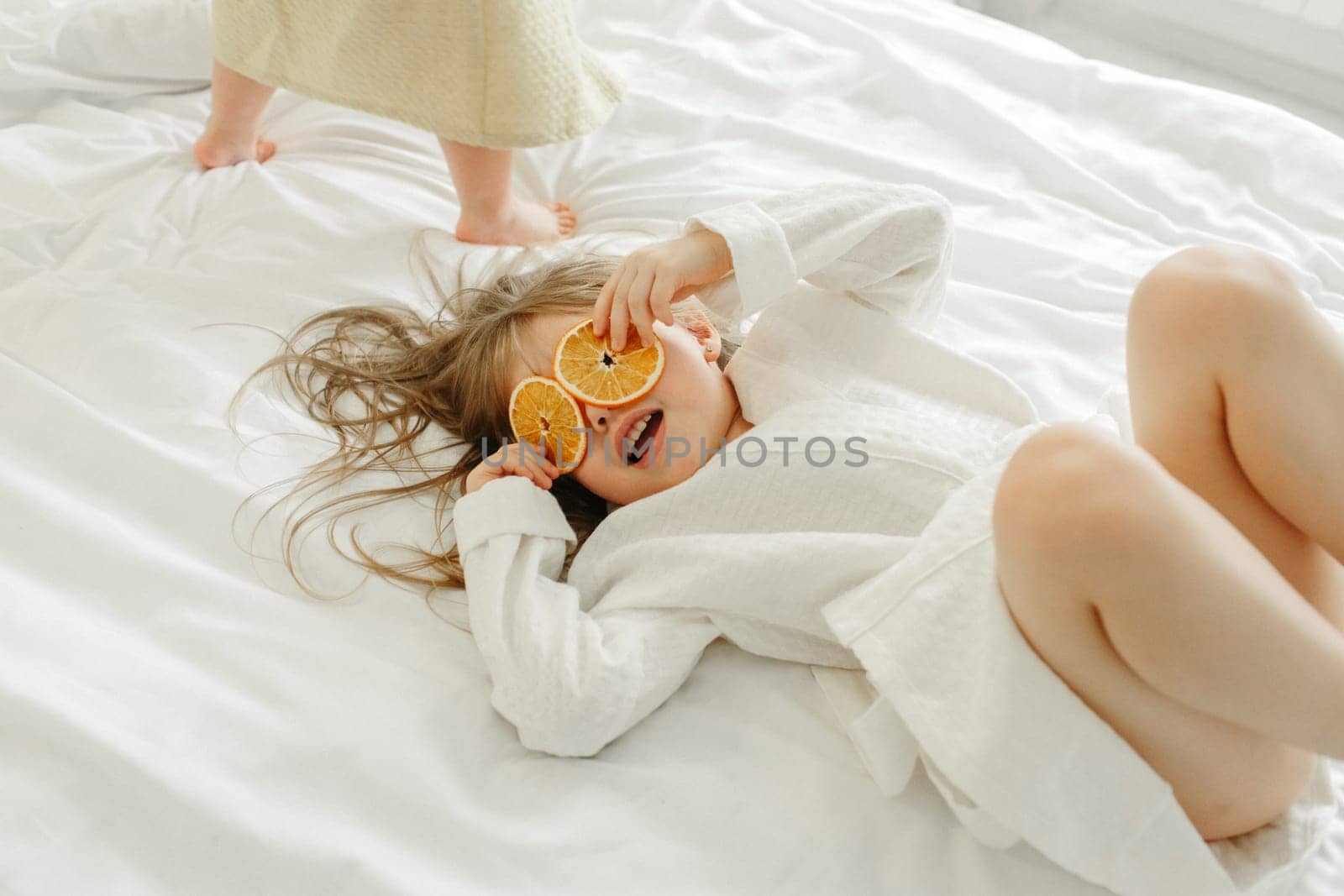 A young girl in a white coat, lying in bed, playing with candied oranges. by Sd28DimoN_1976