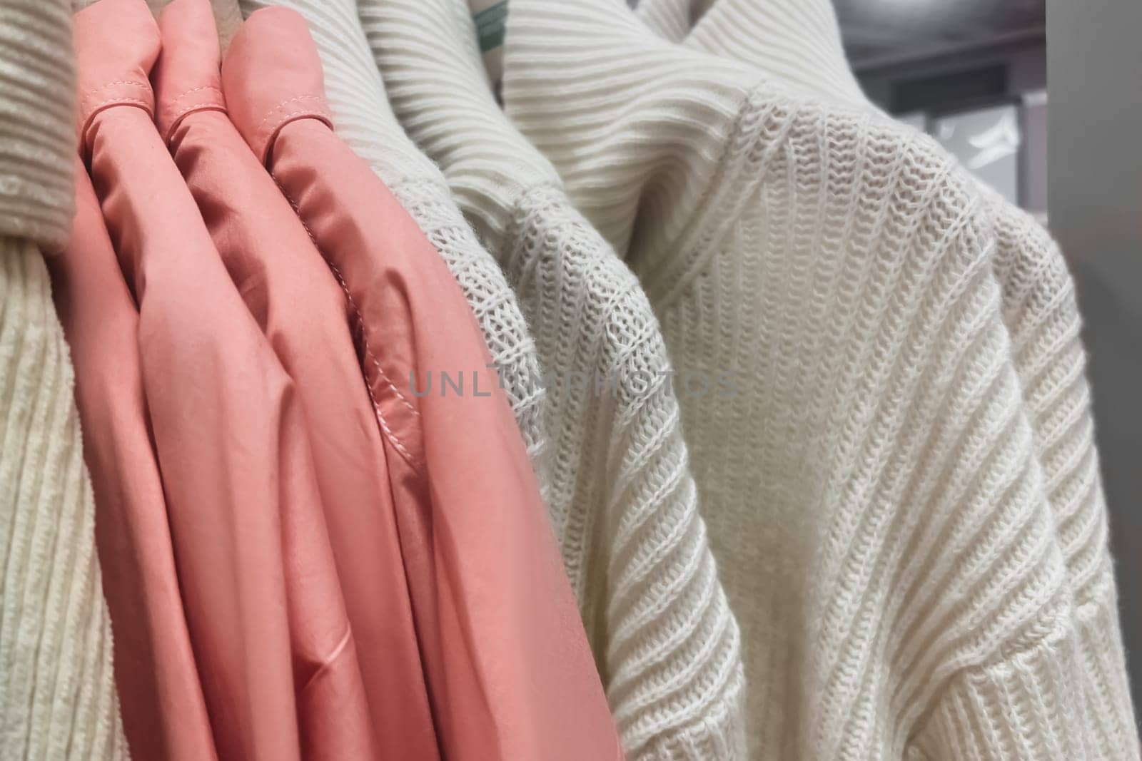 Pullover and sweaters hang on a hanger in the store Row