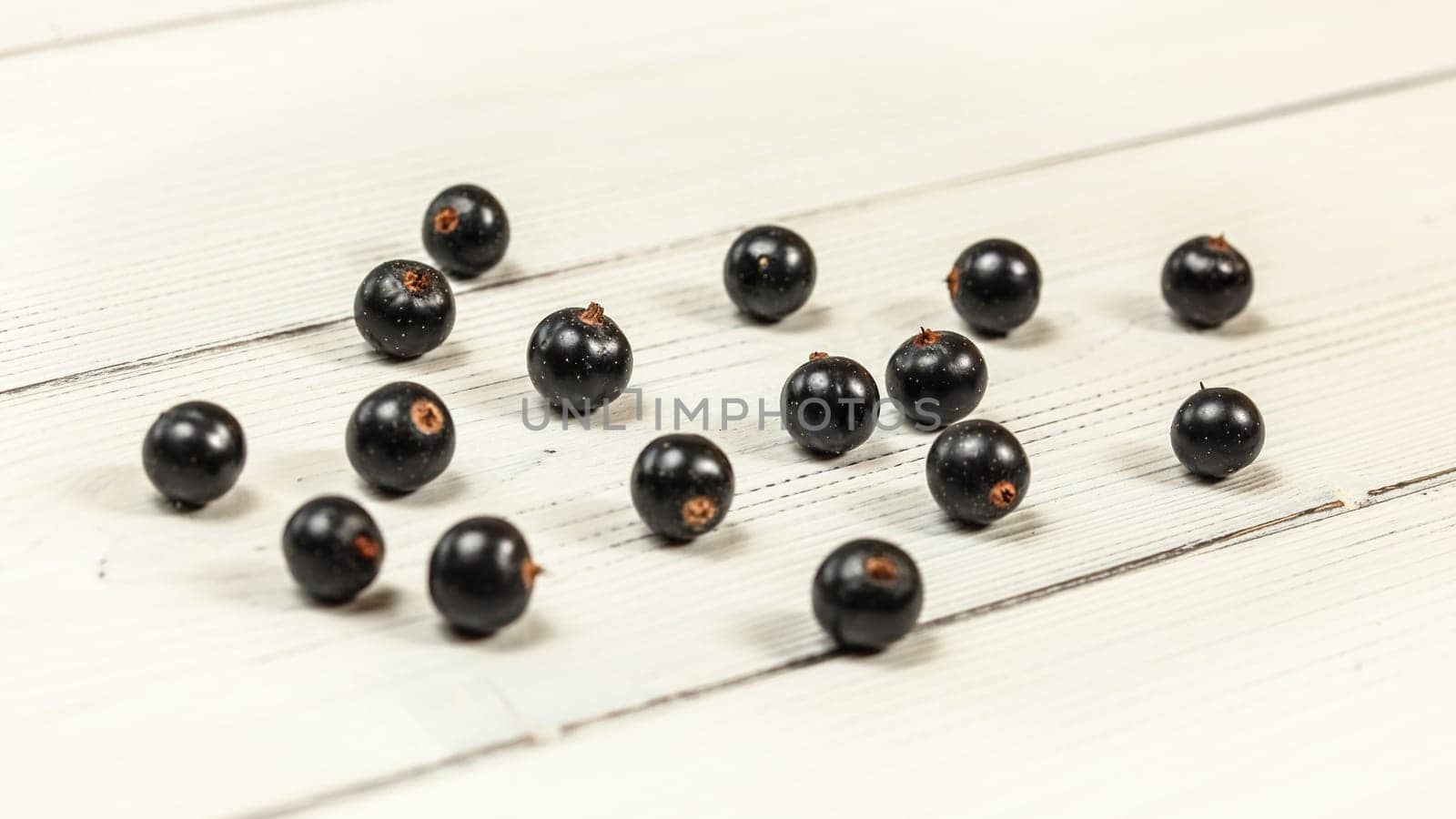Blackcurrants (Ribes nigrum) spilled on white boards desk