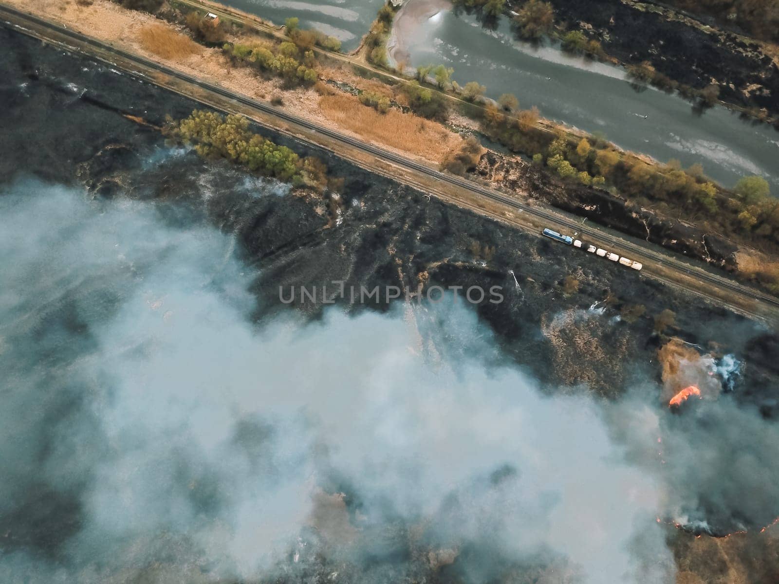 Aerial drone flight over burning hill side with thick white smoke blown off frame . Natural disaster due to extreme heat and climate change by voffka23