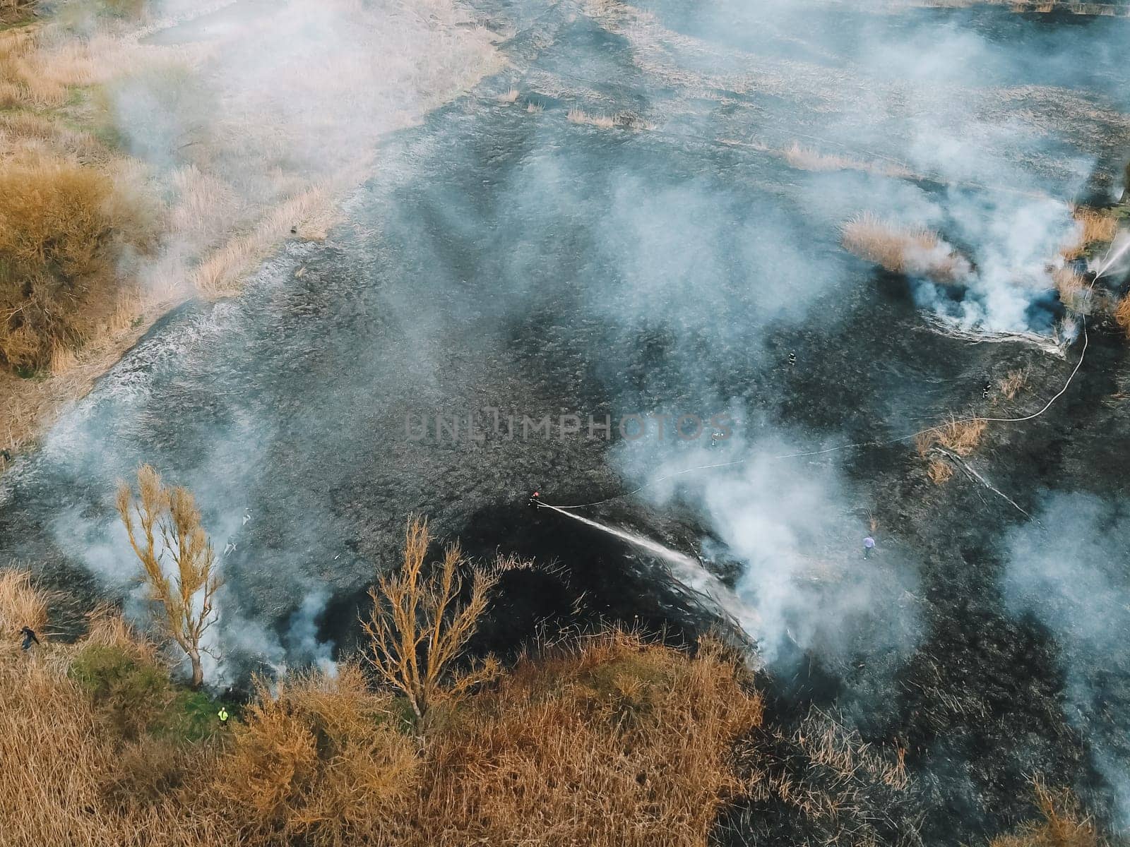 Aerial view of firefighter in equipment extinguish a forest fire with a fire hose by voffka23