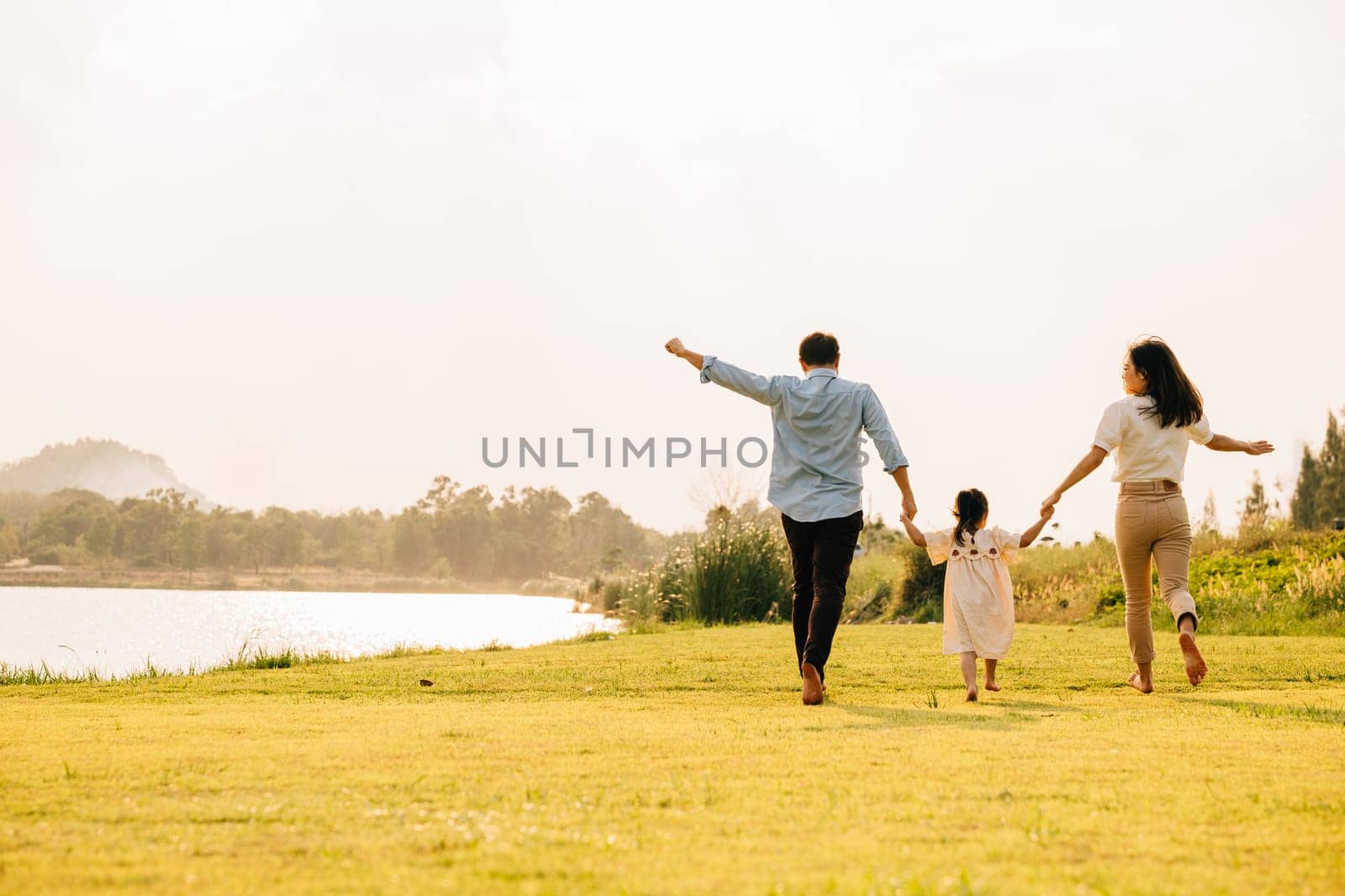 Back view of Happy Asian family walking and playing together in a scenic garden by Sorapop