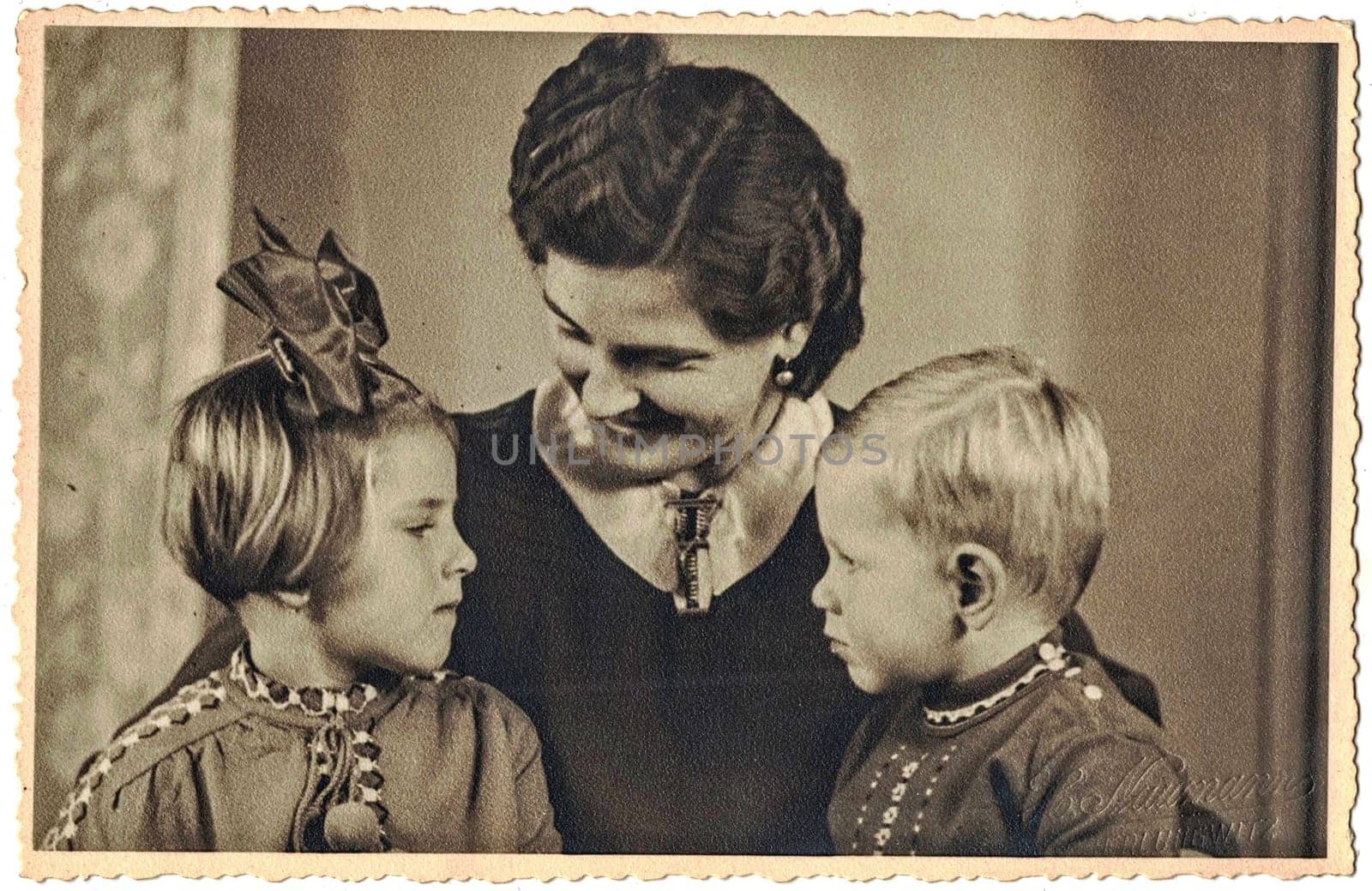 The vintage photo shows family photo, mum and children - girl and boy. Studio portrait by roman_nerud