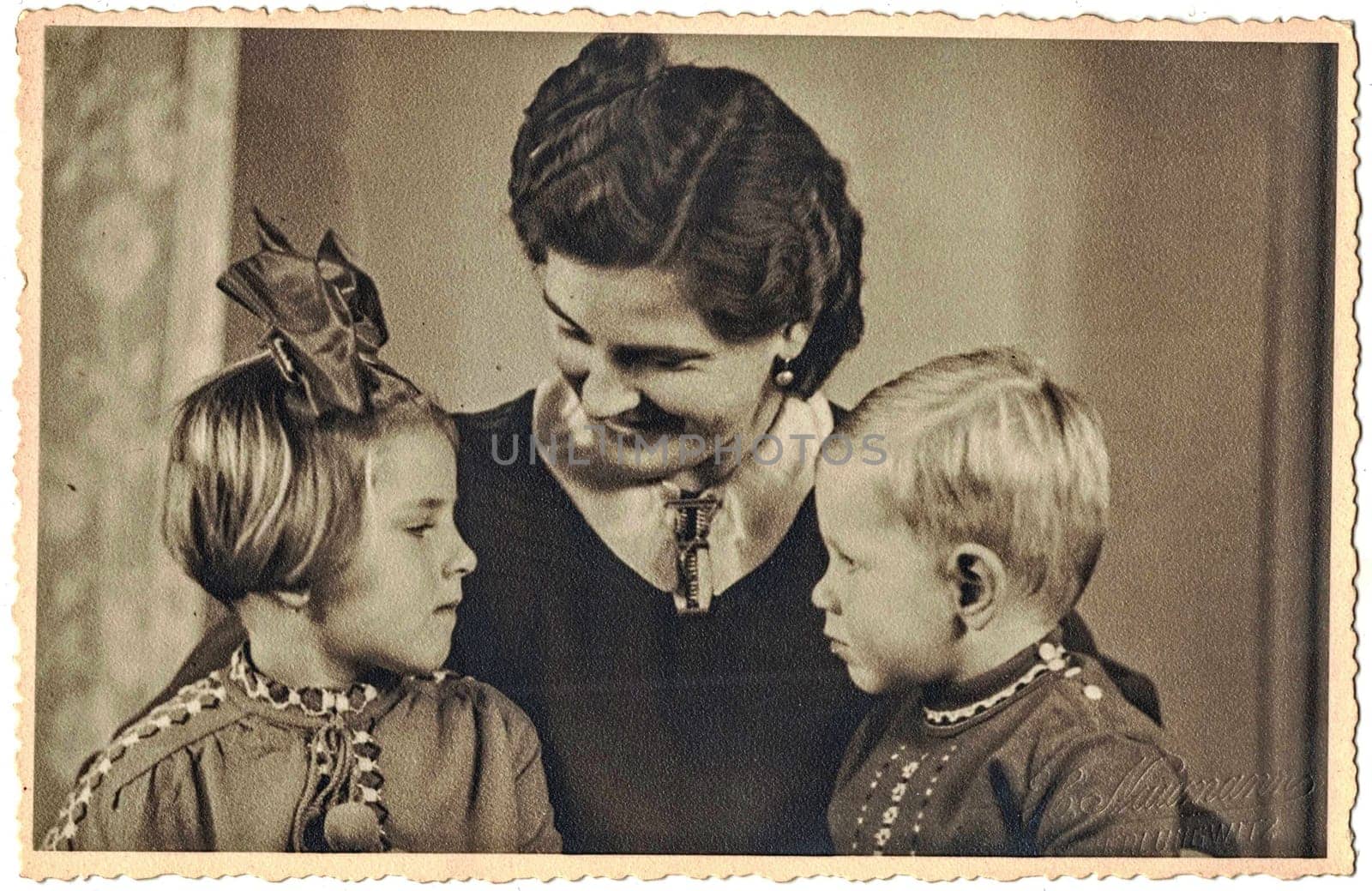 OBERLUNGWITZ, GERMANY - NOVEMBER 30, 1939: The vintage photo shows family photo, mum and children - girl and boy. Studio portrait.