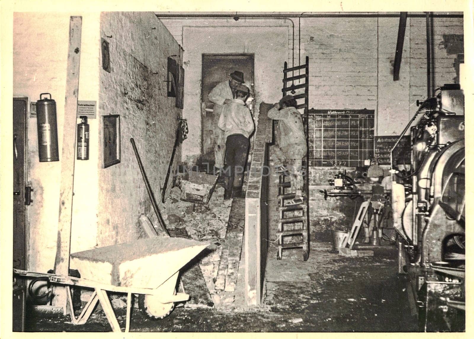 FRAUREUTH, EAST GERMANY - MARCH 3, 1965: The retro photo shows bricklayers working. Authentic photo from Communist Bloc