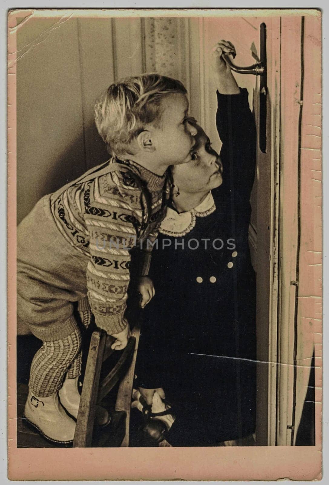 The vintage photo shows two children-boy and girl curiously looking for something... Christmas presents, birthday presents, something interesting in the television... by roman_nerud