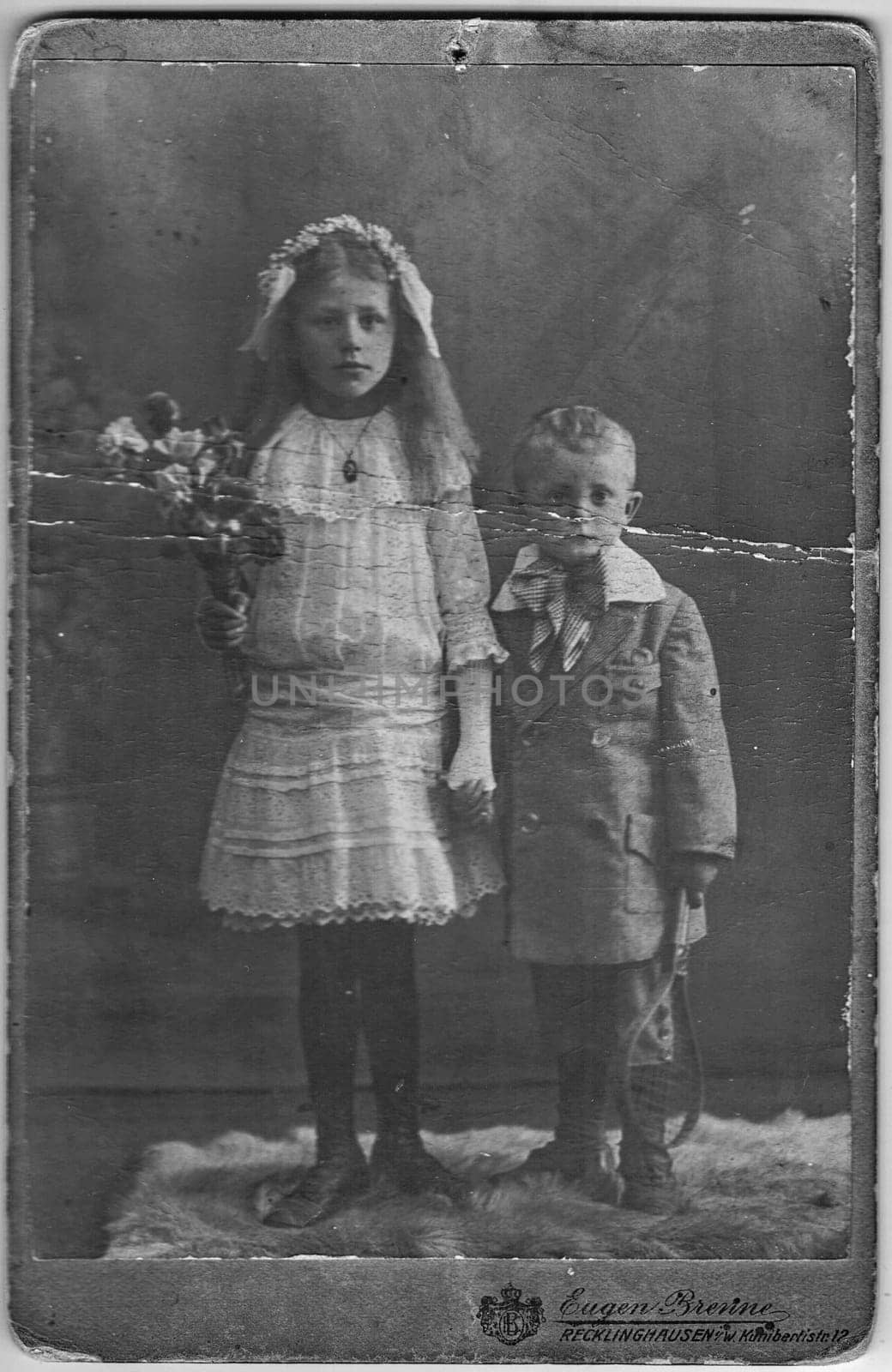 RECKLINGHAUSEN, GERMANY - CIRCA 1910s: Vintage photo shows siblings - sister and brother. About 10 and 7 years old. Studio black and white portrait.