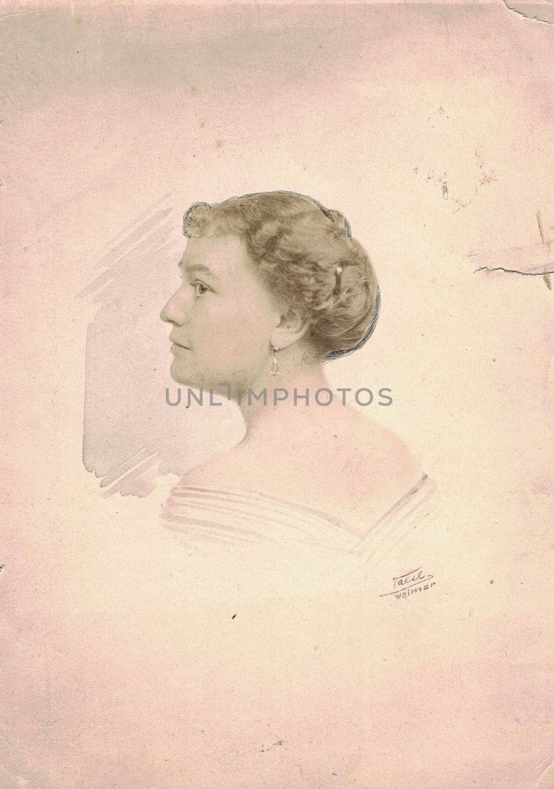 GERMANY - CIRCA 1910s: Vintage photo shows dreamy portrait of woman. Woman wears earrings, the neck and body is hand painted additionally. Black & white antique photography.
