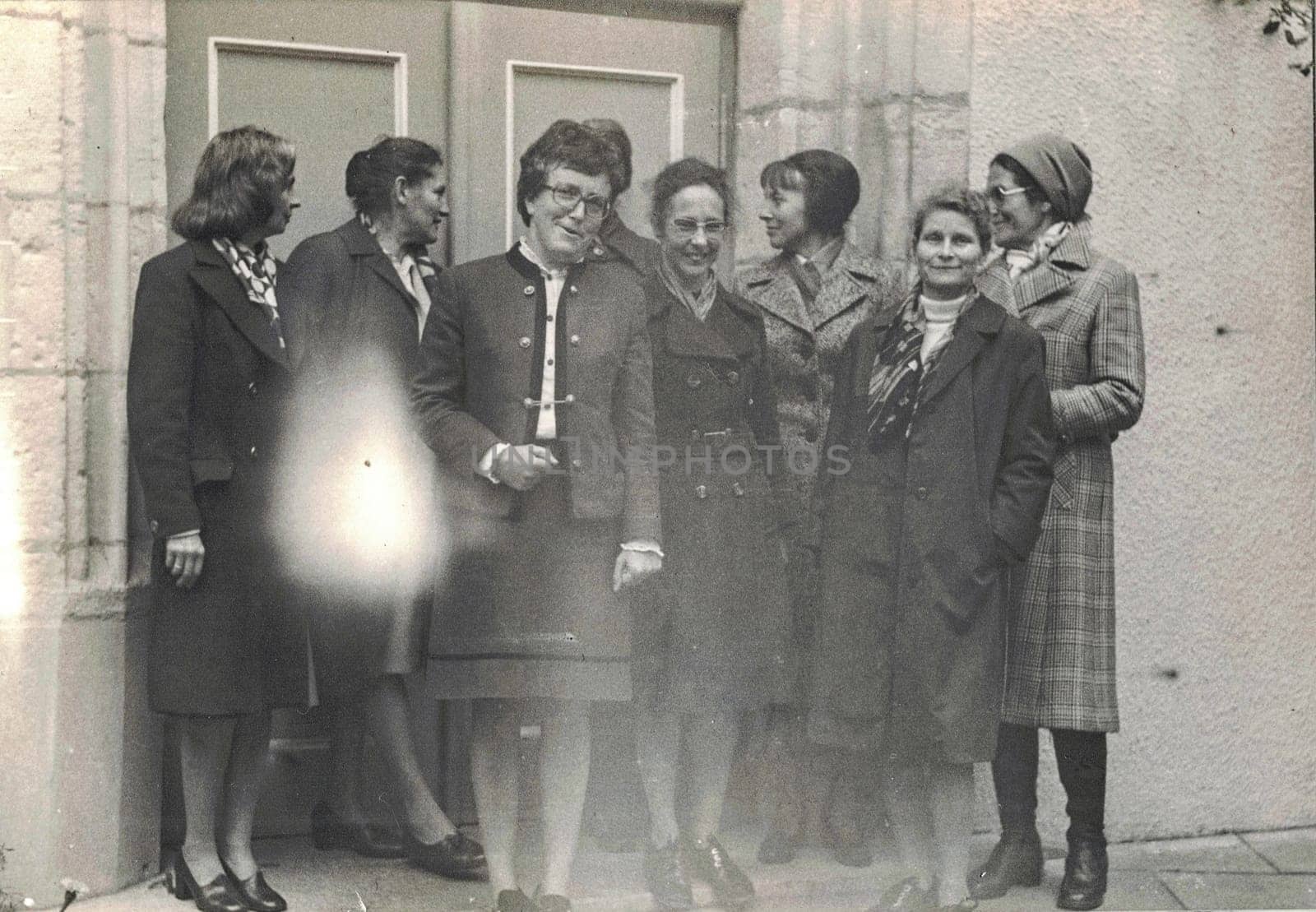 Retro photo shows group of ladies pose in front of building. Photo has imperfection. by roman_nerud