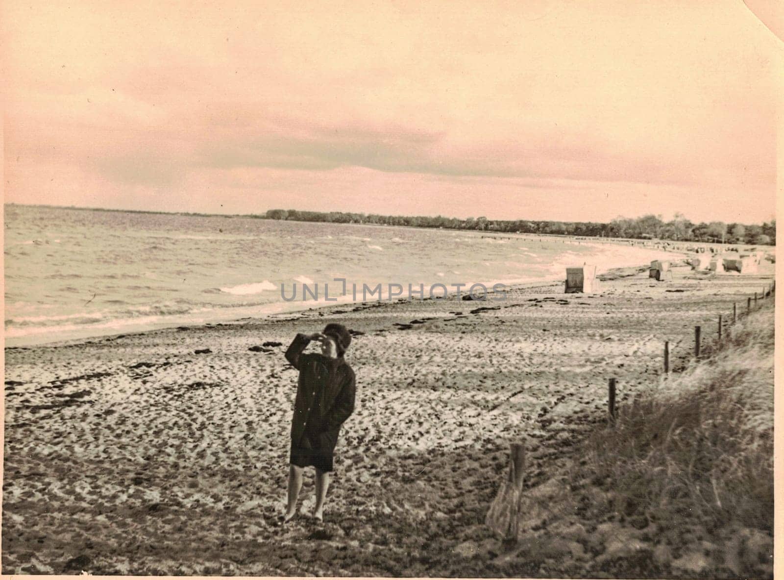 GERMANY - CIRCA 1960s: Retro photo shows woman seeing sealine at the seashore of the Baltic Sea. Retro black and white photo.