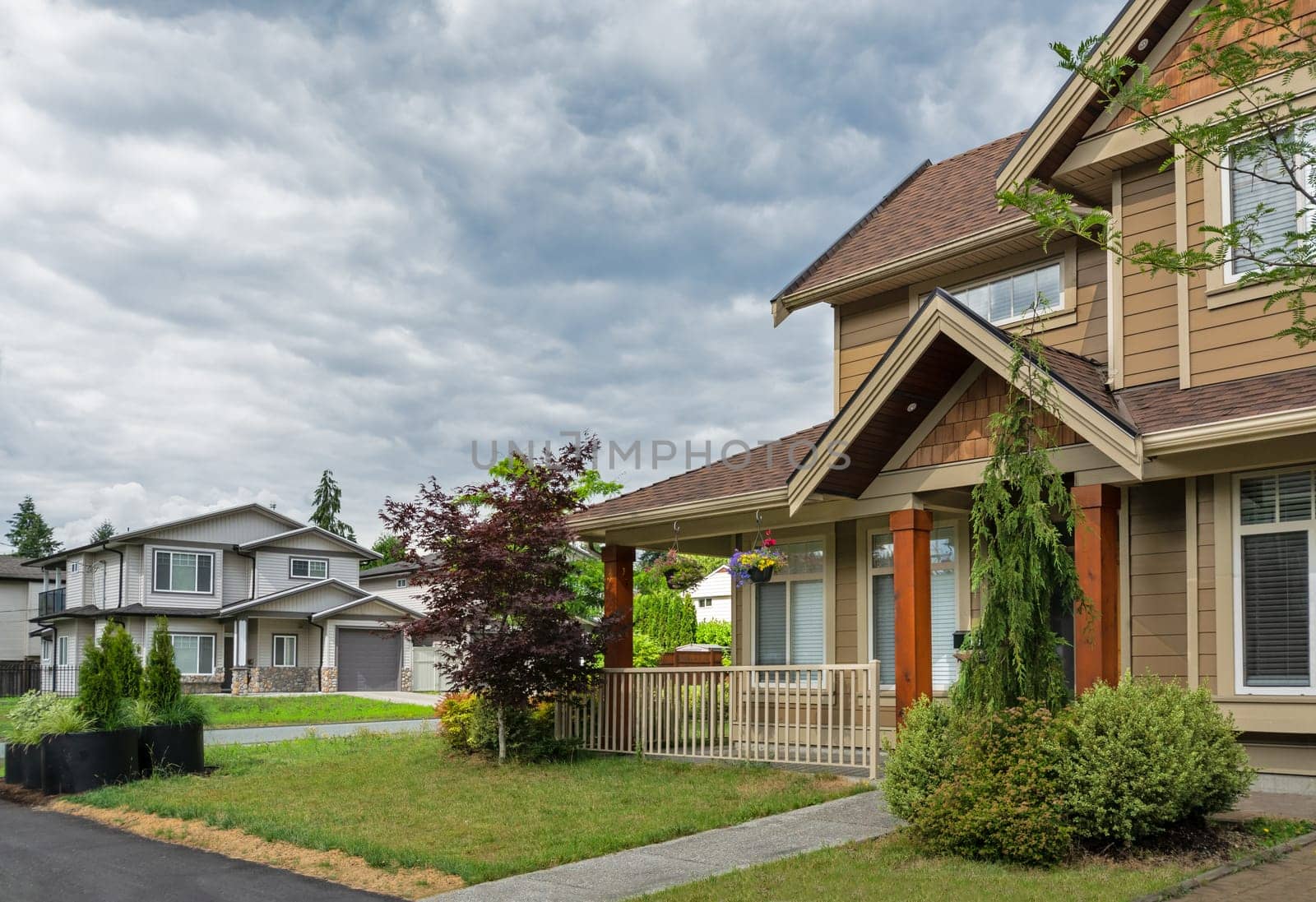 A perfect neighbourhood. Street view in suburban residential area on cloudy sky background.