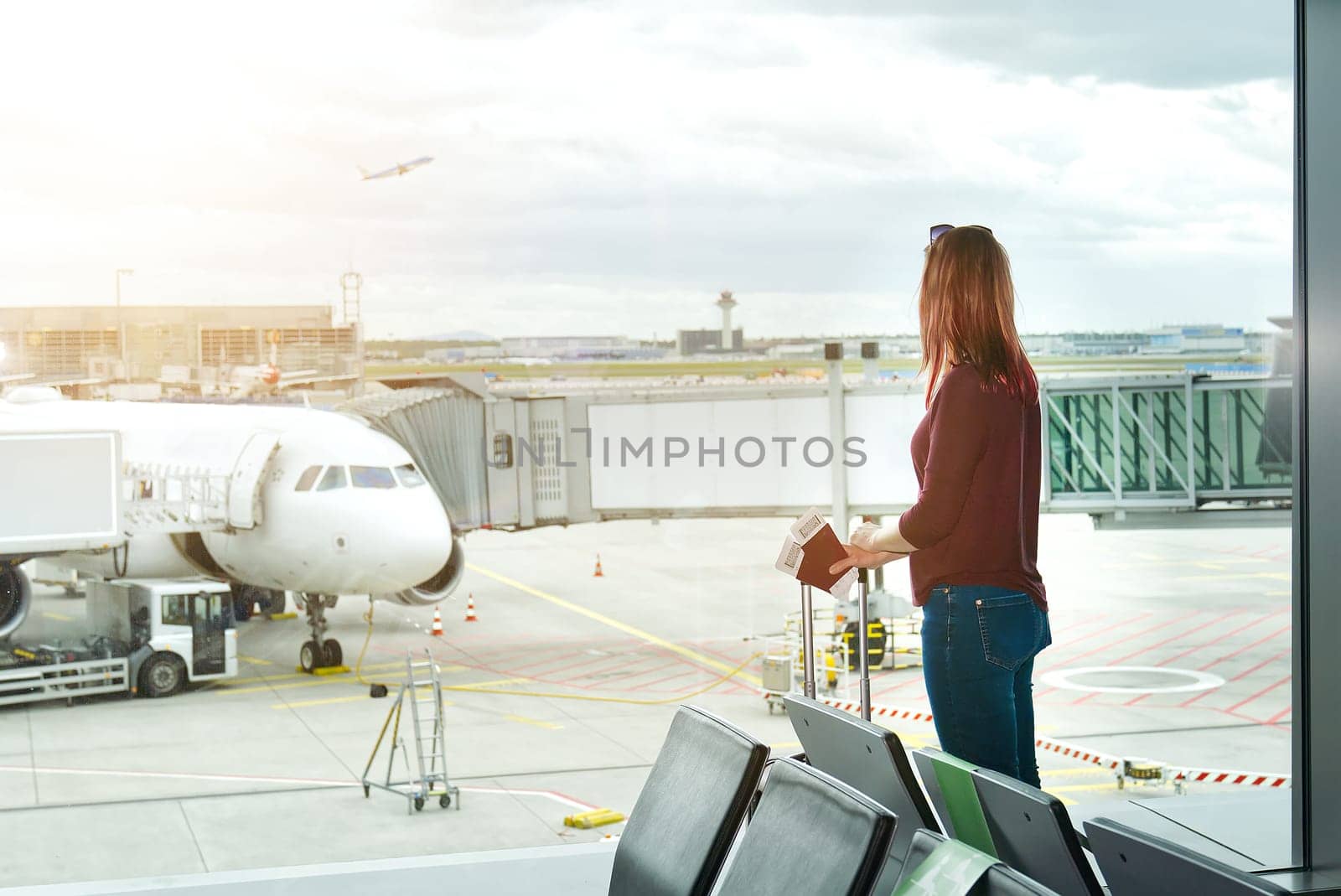 Woman at the airport window and flight departure, Airport Terminal: Happy Traveling Looks Around by PhotoTime
