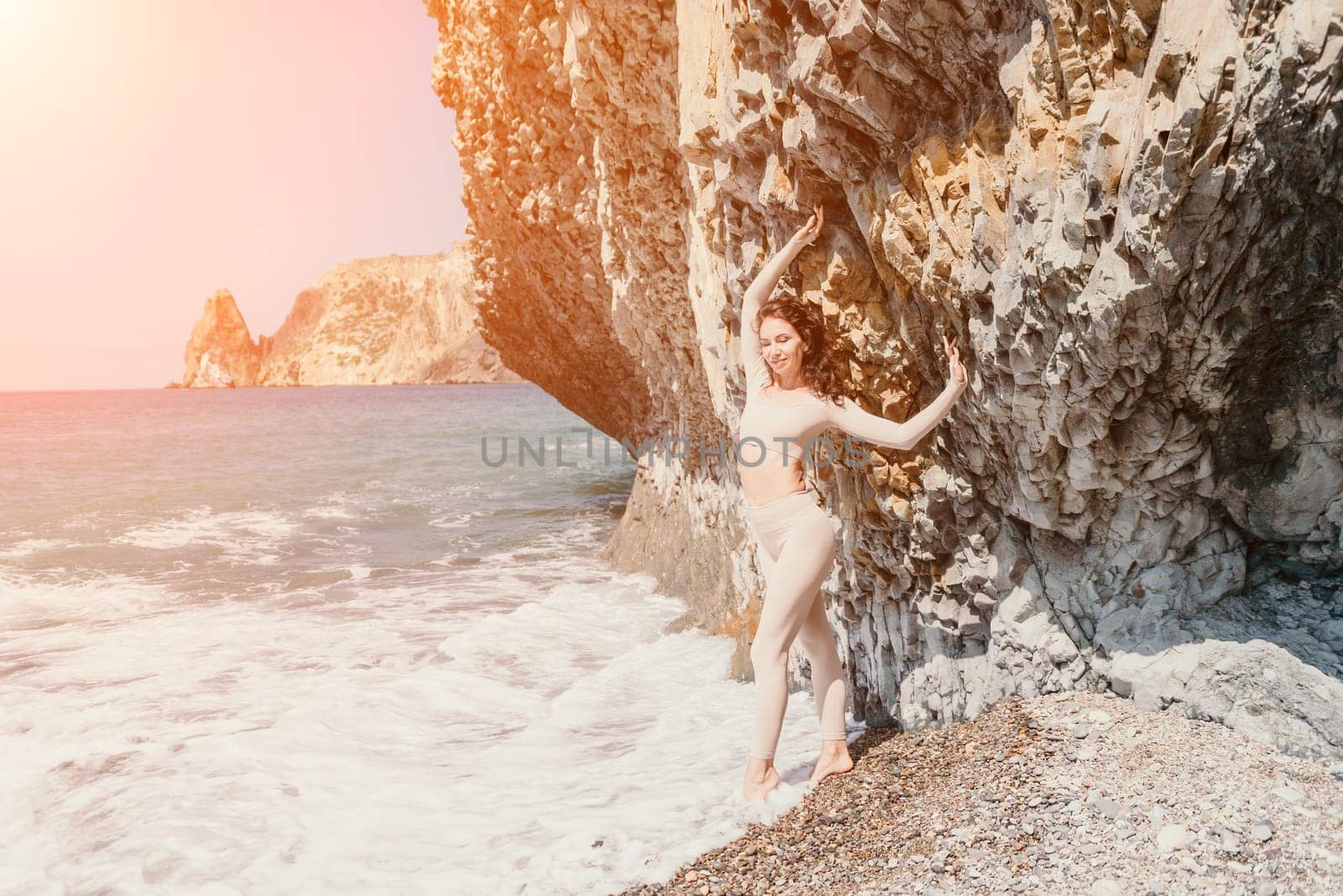 Woman travel sea. Sporty happy middle aged posing on a beach near the sea on background of volcanic rocks, like in Iceland, sharing travel adventure journey by panophotograph