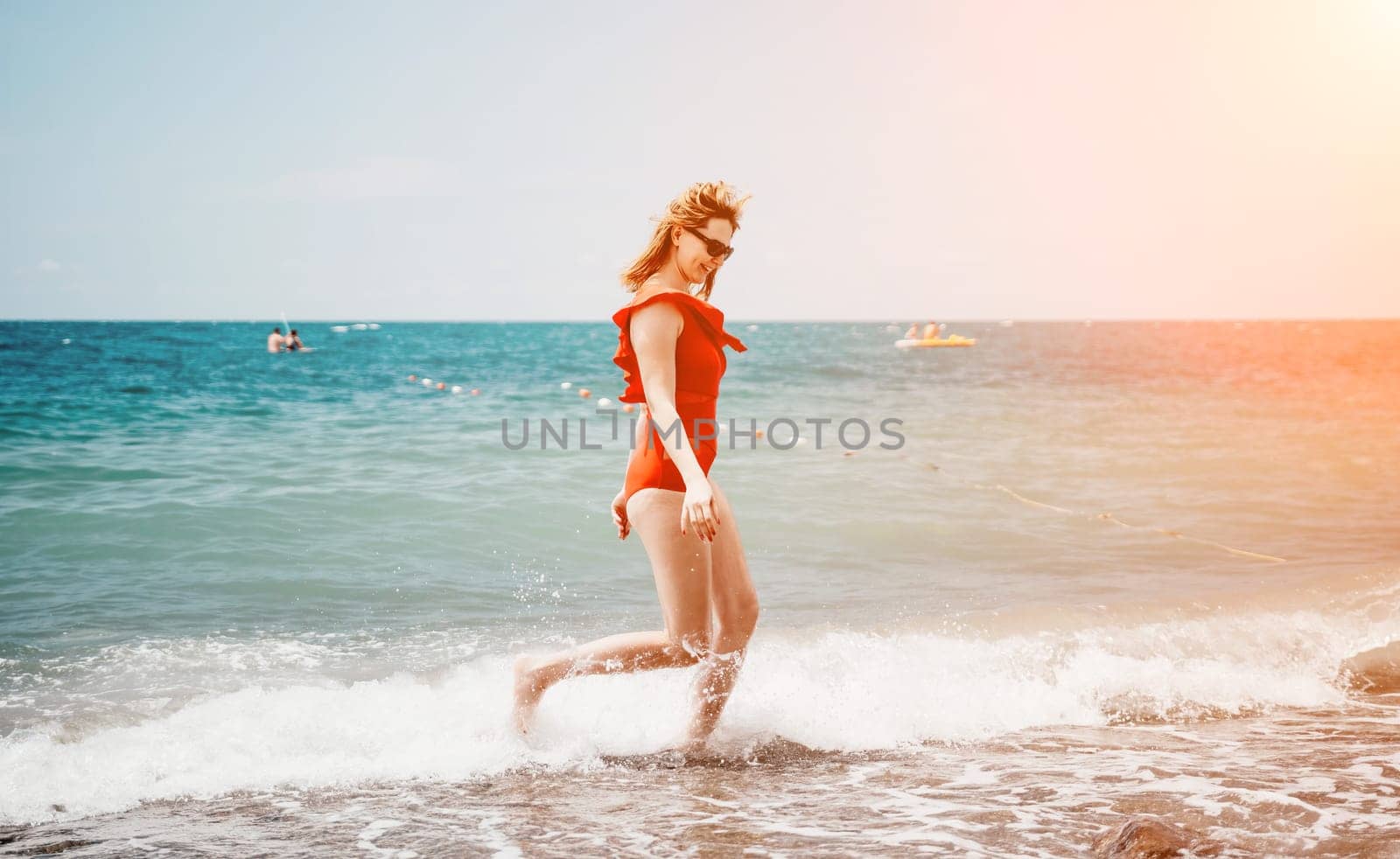 Young happy woman walks carefree on the seaside. Happy lady in red bikini. Portrait beautiful young woman relax smile around beach sea ocean in holiday vacation travel trip.