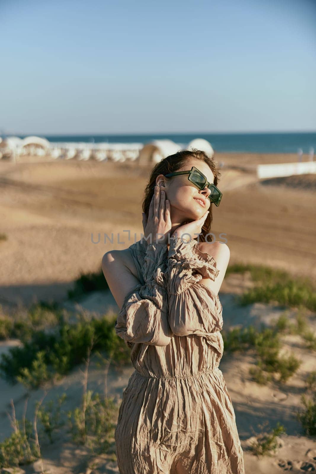 portrait of a woman in a light dress and sunglasses turning her head away from the camera. High quality photo