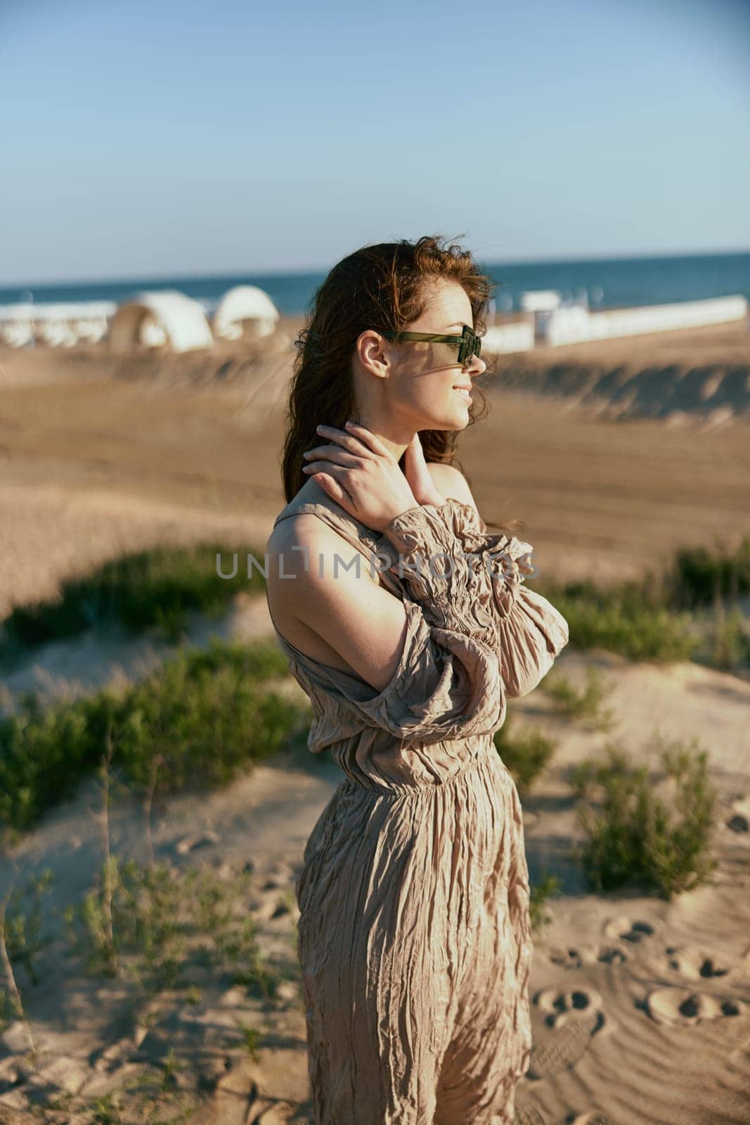 portrait of a woman in a light dress and sunglasses turning her head away from the camera. High quality photo