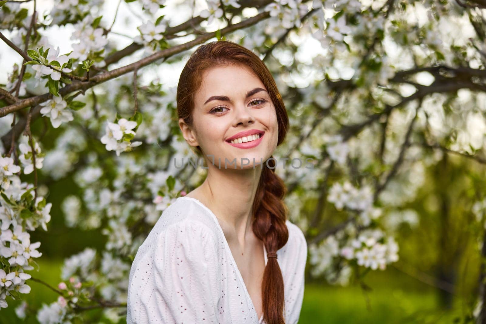 Beautiful young woman. model in white dress stands in white flowers. Horizontal photo. copy space. by Vichizh