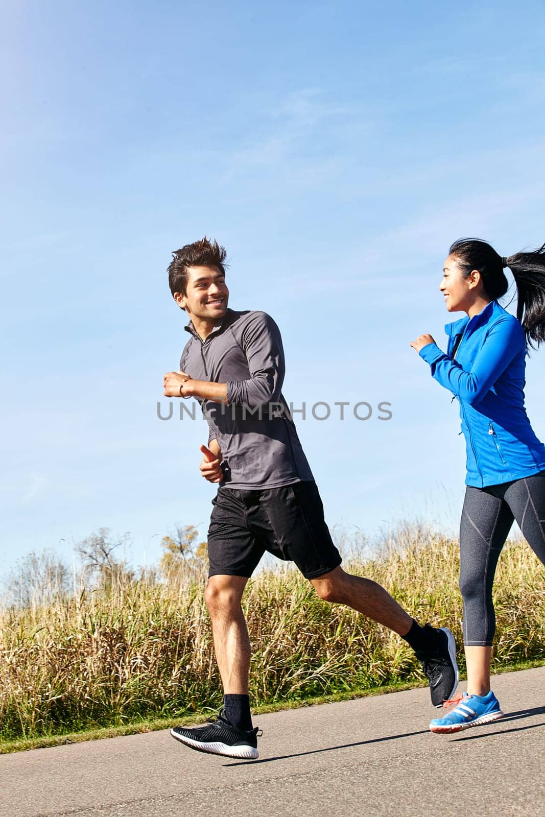 Running generates the best of moods. a sporty young couple exercising together outdoors. by YuriArcurs